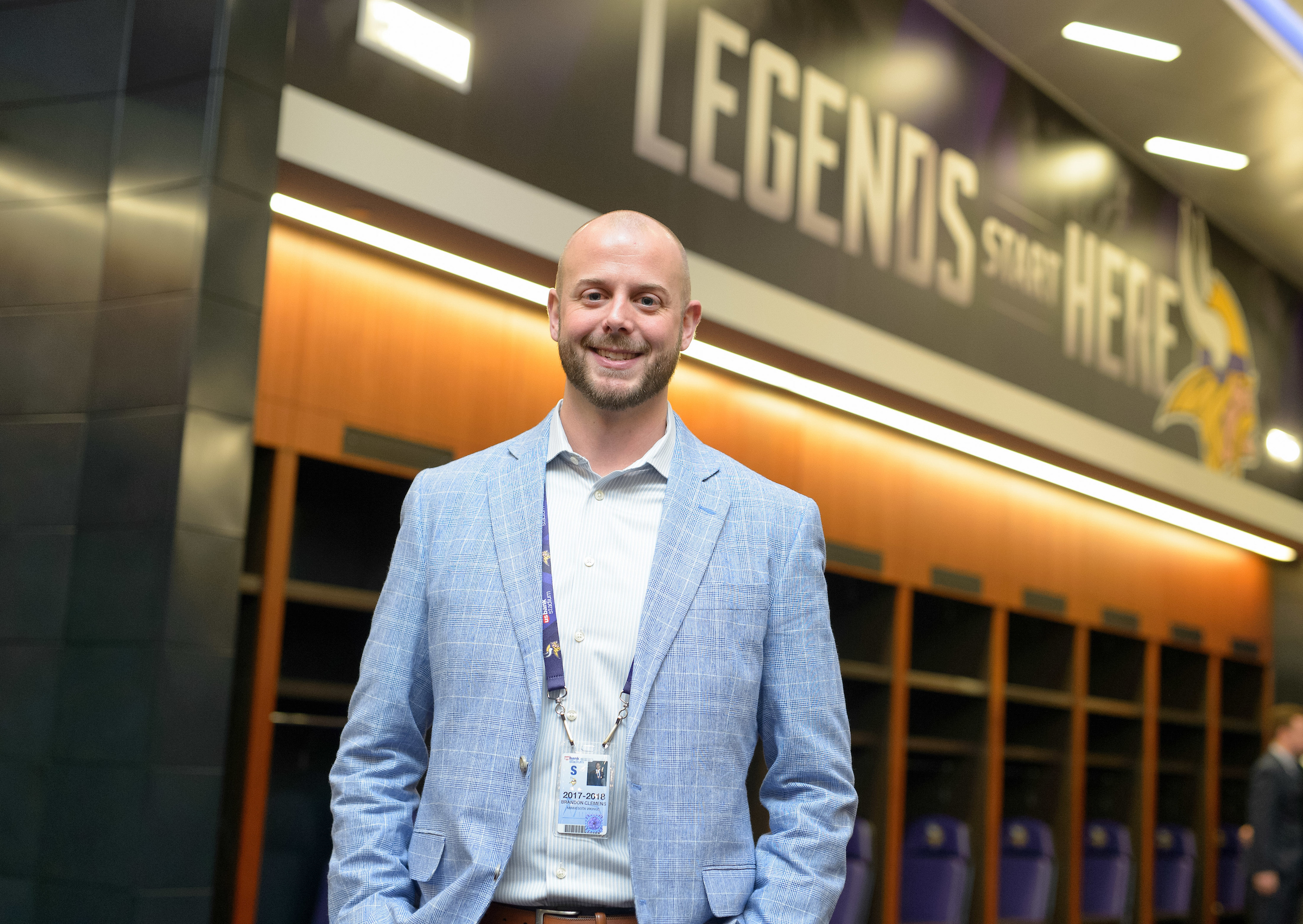 University of Iowa graduate Brandon Clemens stands inside a facility of the Minnesota Vikings, the words Legends Start Here are written on the wall behind him