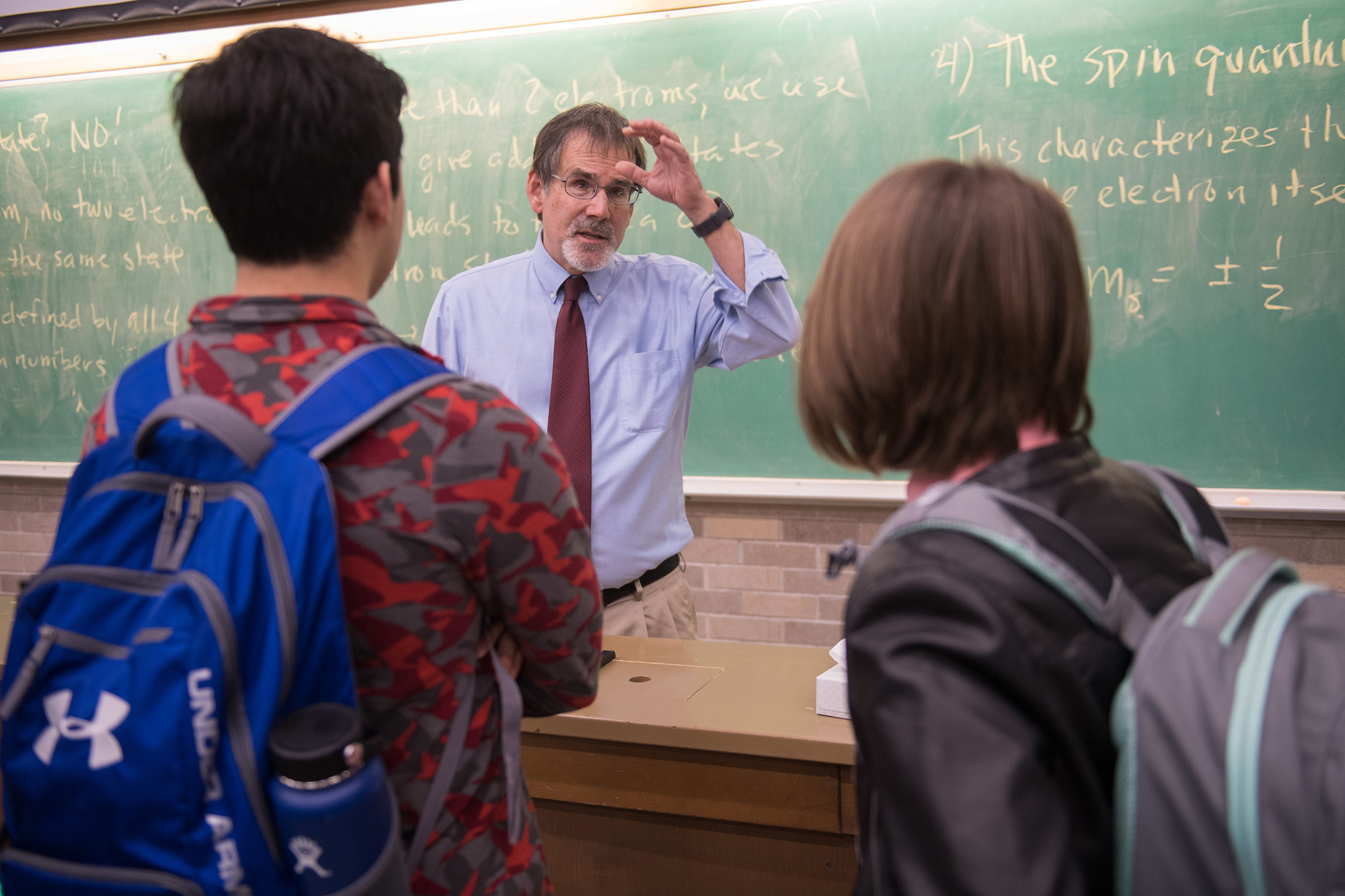 university of iowa professor craig kletzing conversing with two of his students in a classroom