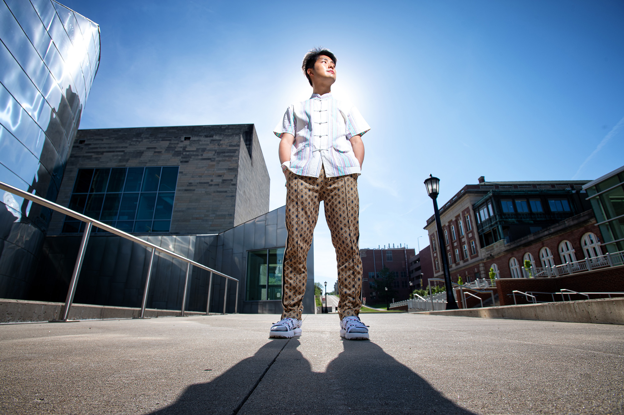 University of Iowa Master of Fine Arts student Hao Zhou standing on campus on a sunny day, looking to his left