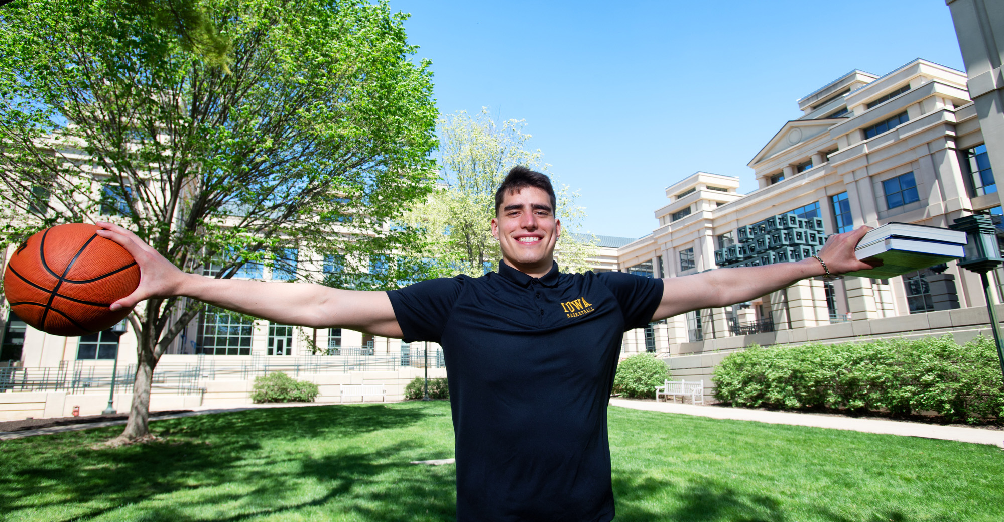 Luka Garza on the University of Iowa campus, holding textbooks and a basketball