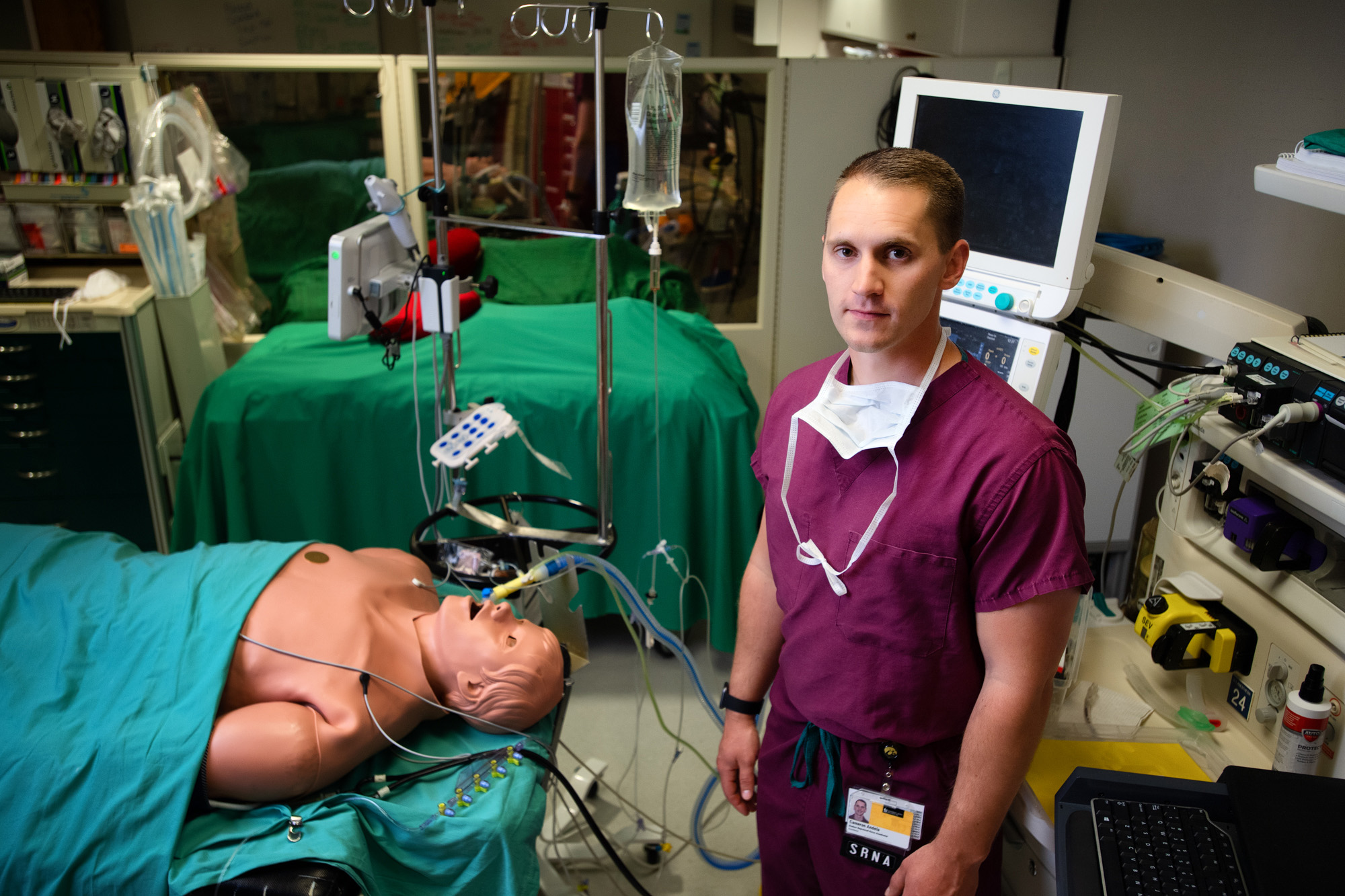 University of Iowa student Cameron Andela standing next to a patient simulator