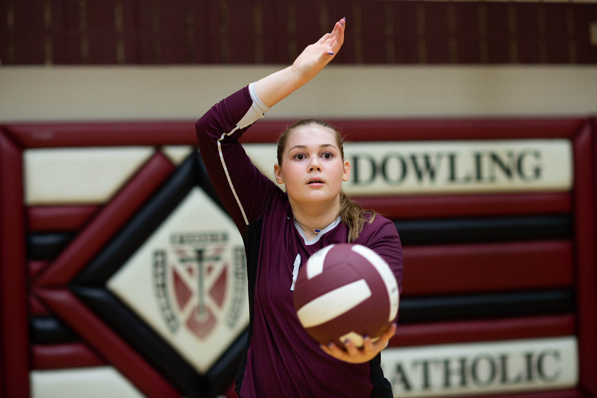 a volleyball player holds the ball in one hand while preparing to serve
