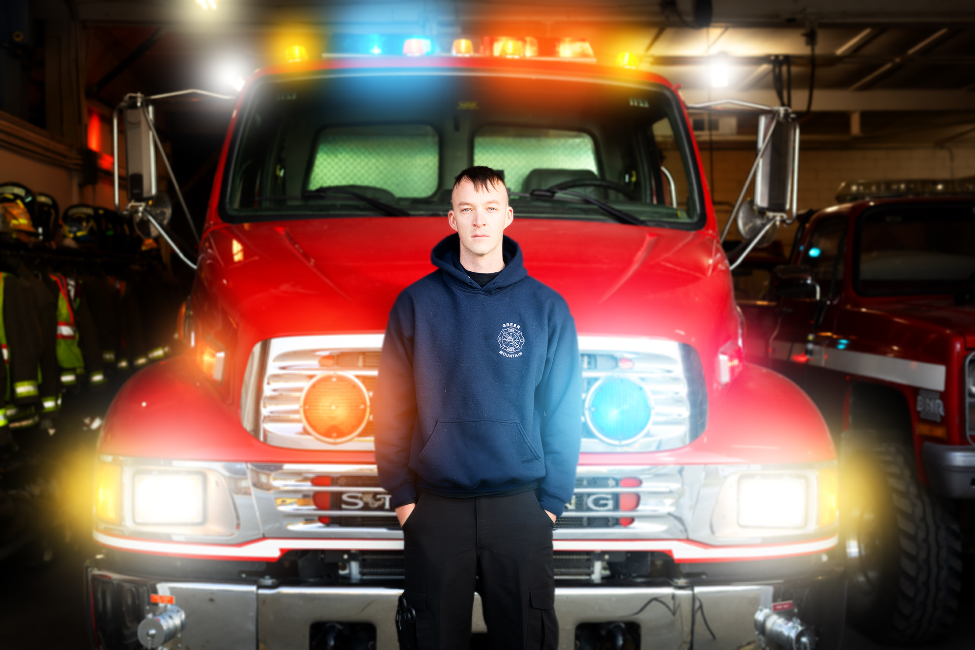 Grant Day standing before a firetruck in a garage stall at a station
