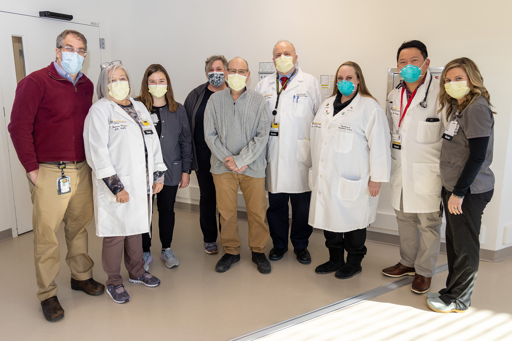 a transplant patient stands with his medical team