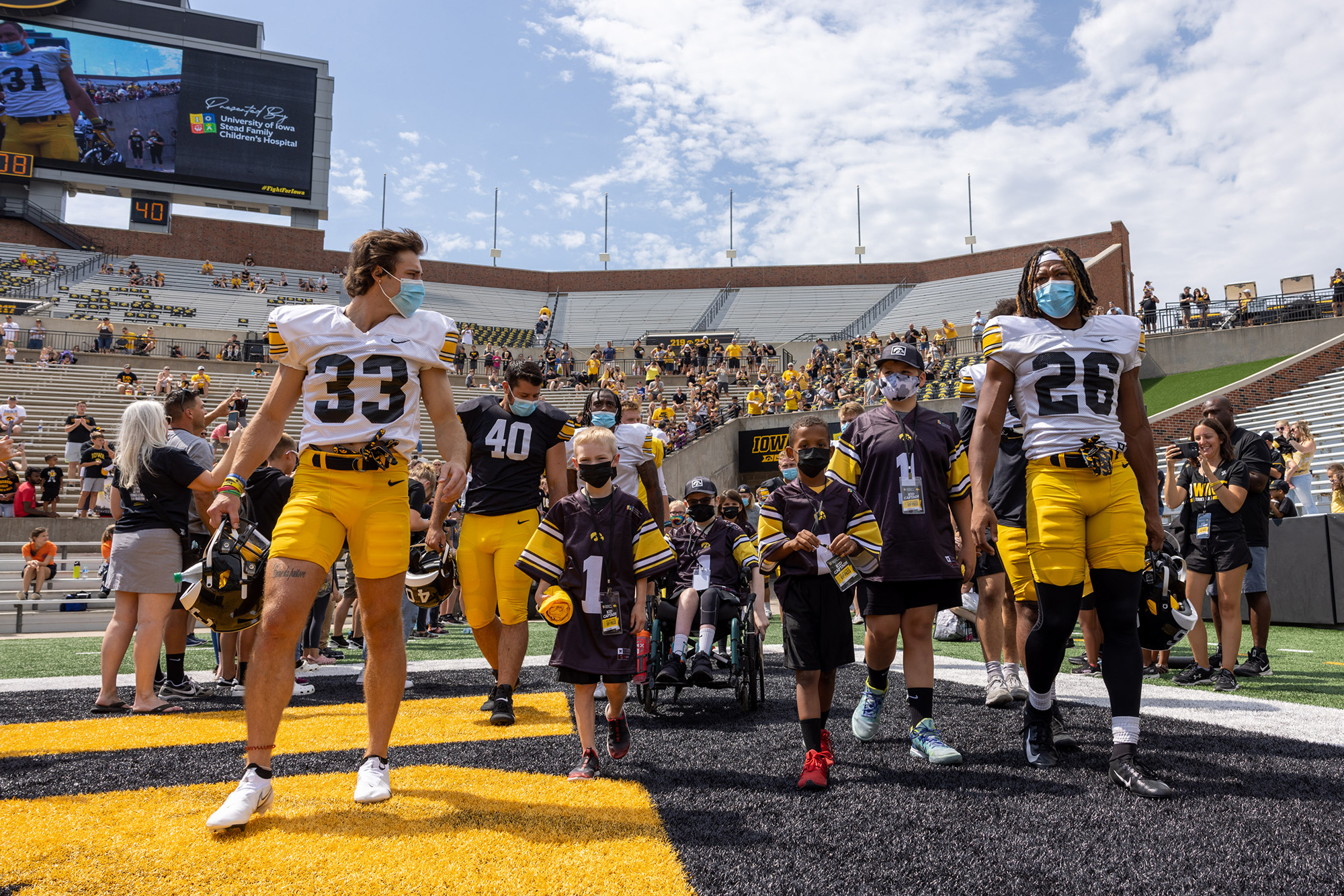Kid Captains walking onto the field at Kinnick Stadium with Iowa football players