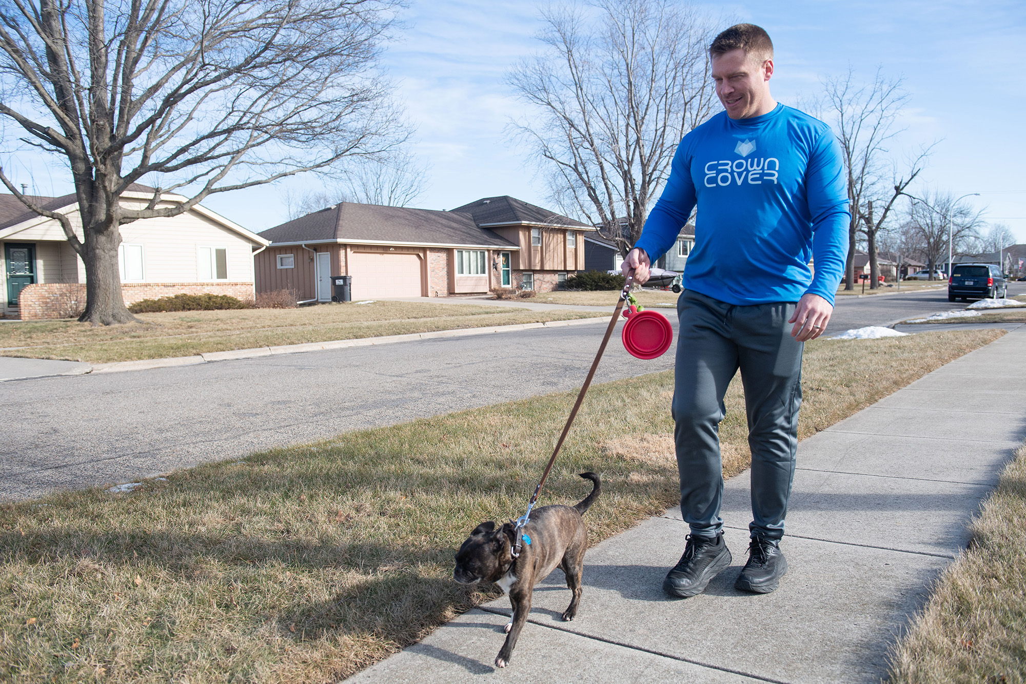 a man walking his dog through a neighborhood