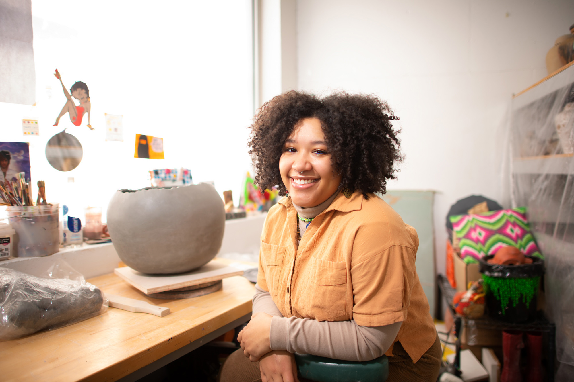 a woman sitting in a room with her artwork