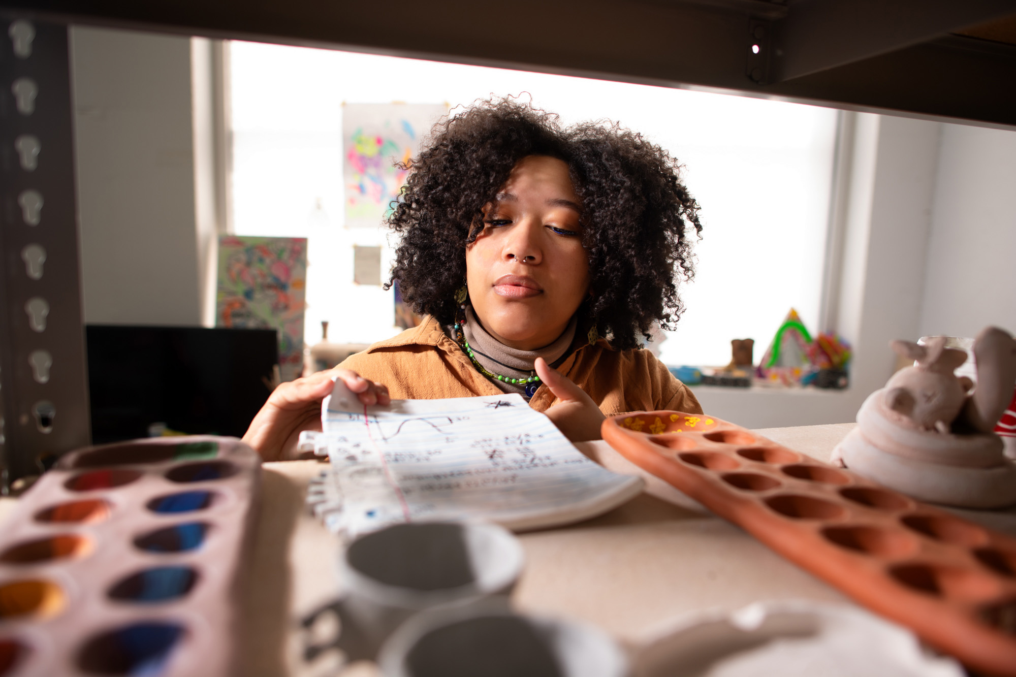 a woman placing artwork on a shelf that contains other art supplies