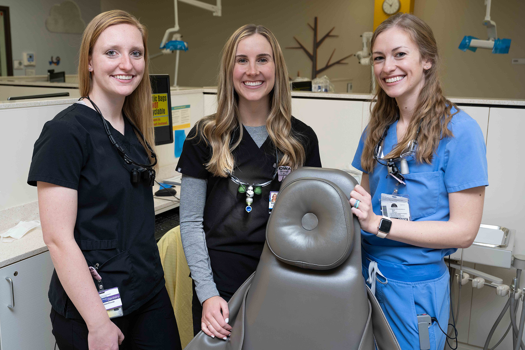 three female dental students standing near a dental chair