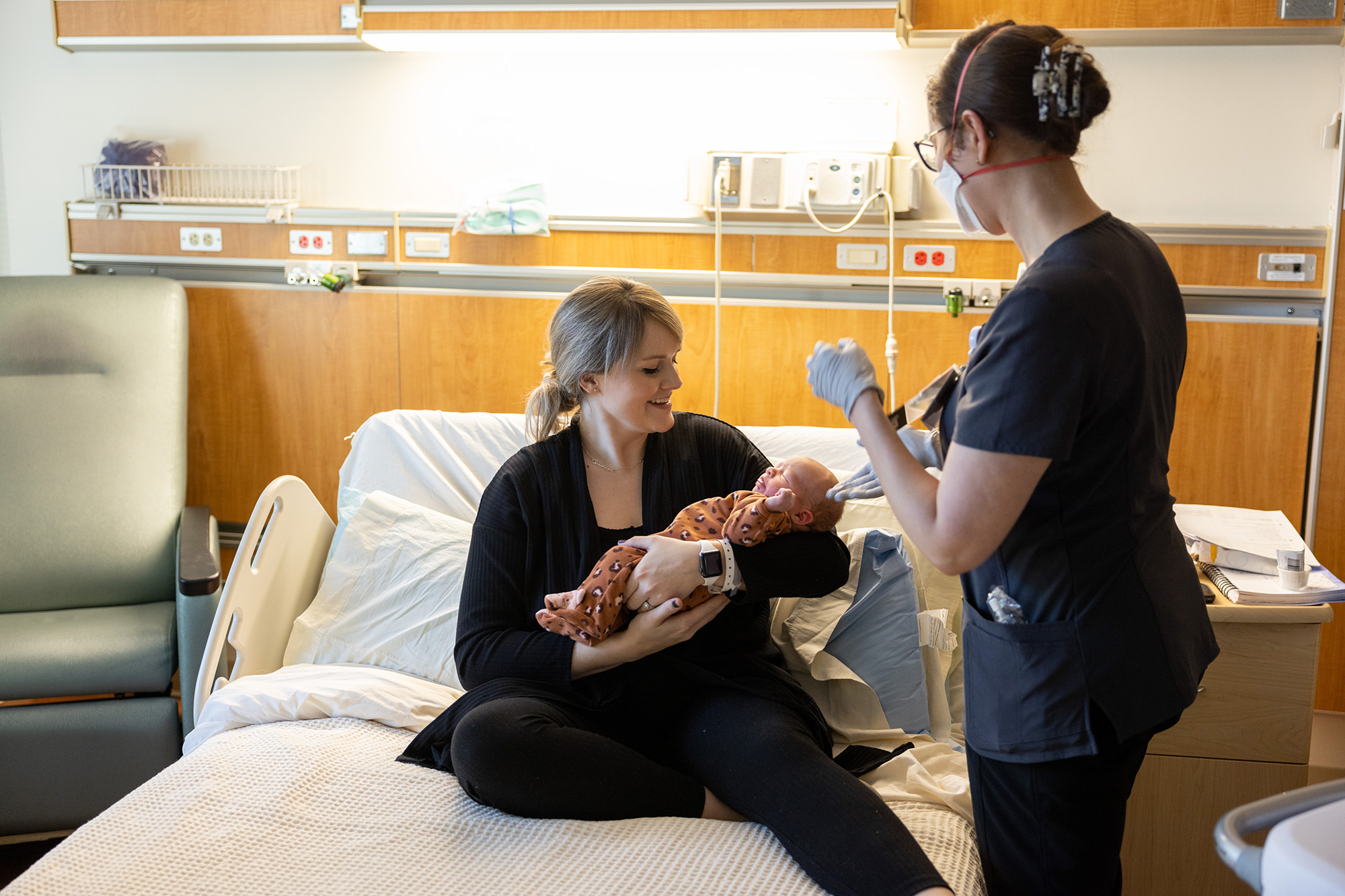 a health care professional speaks with a mother holding a newborn