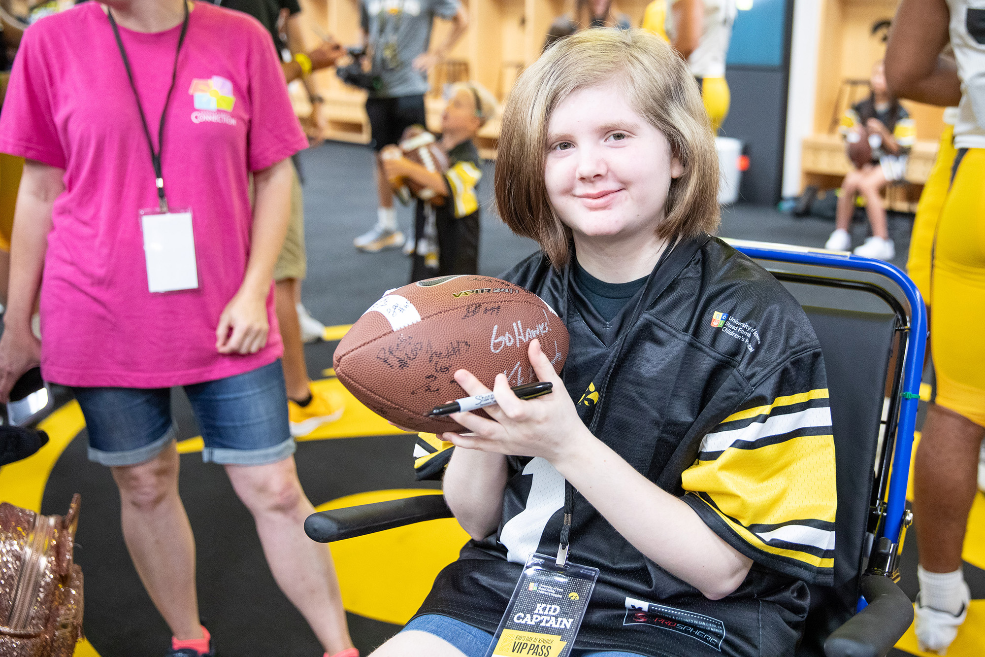 Kid Captain Gabby Ford holding a football while visiting the Hawkeyes' locker room during Kids Day at Kinnick