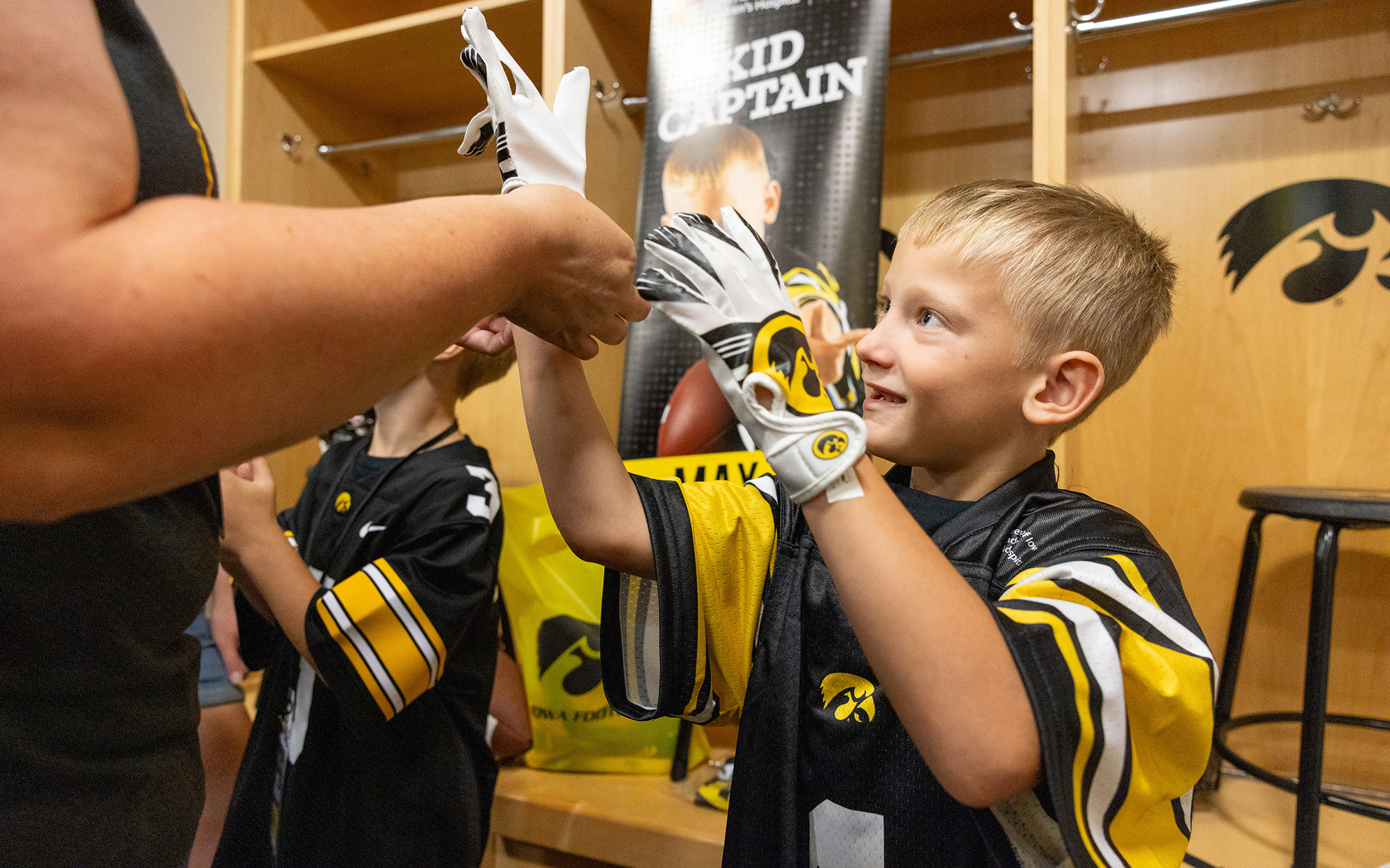 Kid Captain Max Schlee tries on receiver gloves in the locker room during Kids Day at Kinnick