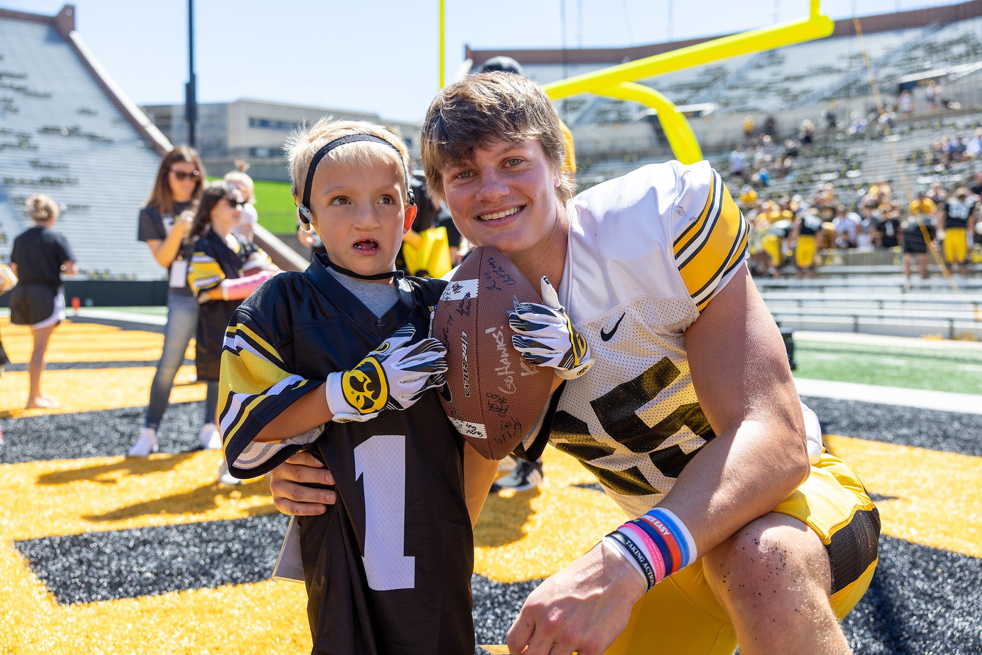 Kid Captain Nile Kron on the field at Kinnick Stadium with current Hawkeye football player and Kid Captain alum Kelby Telander