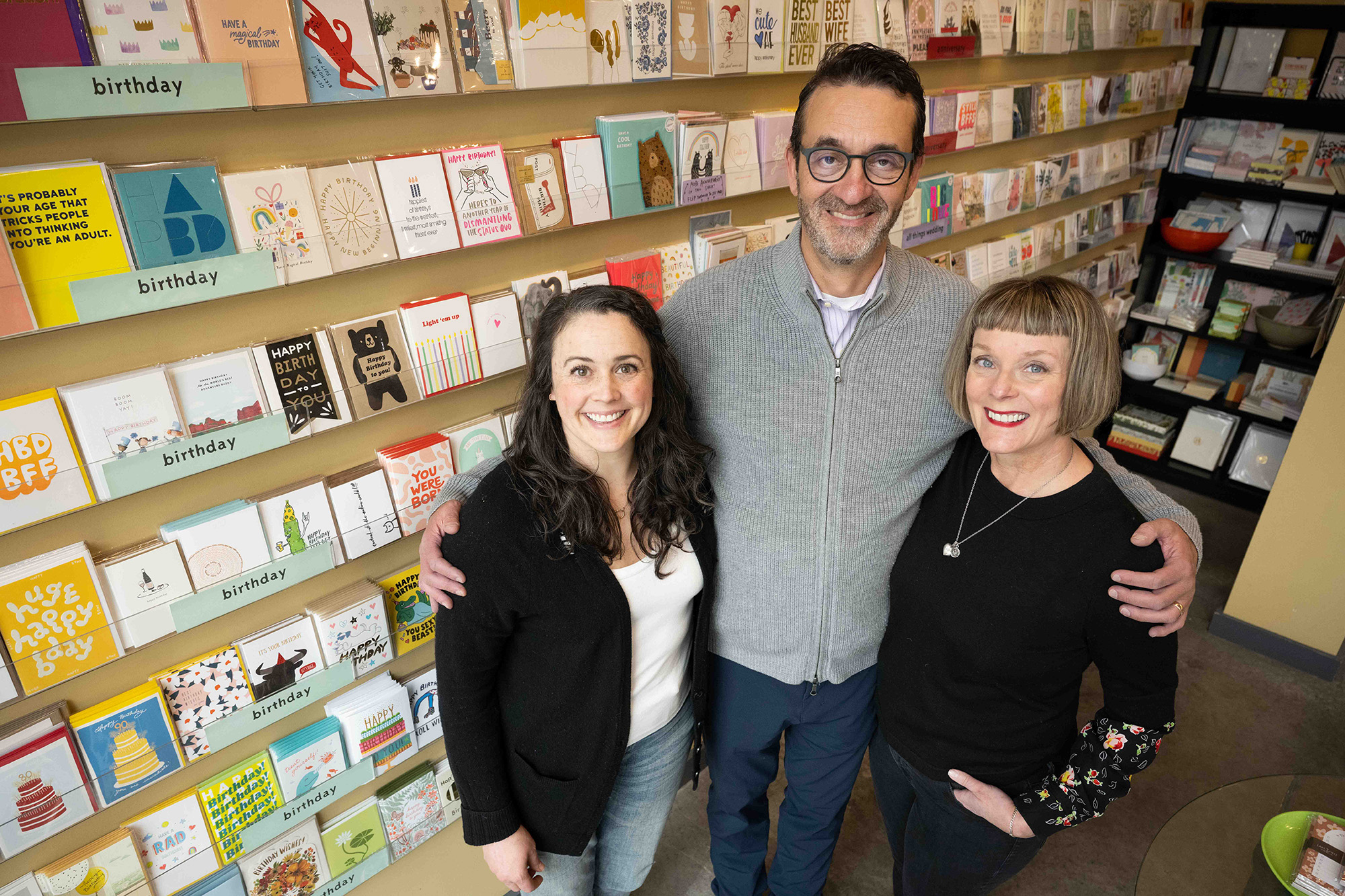 two women and one man stand in a card and stationery shop