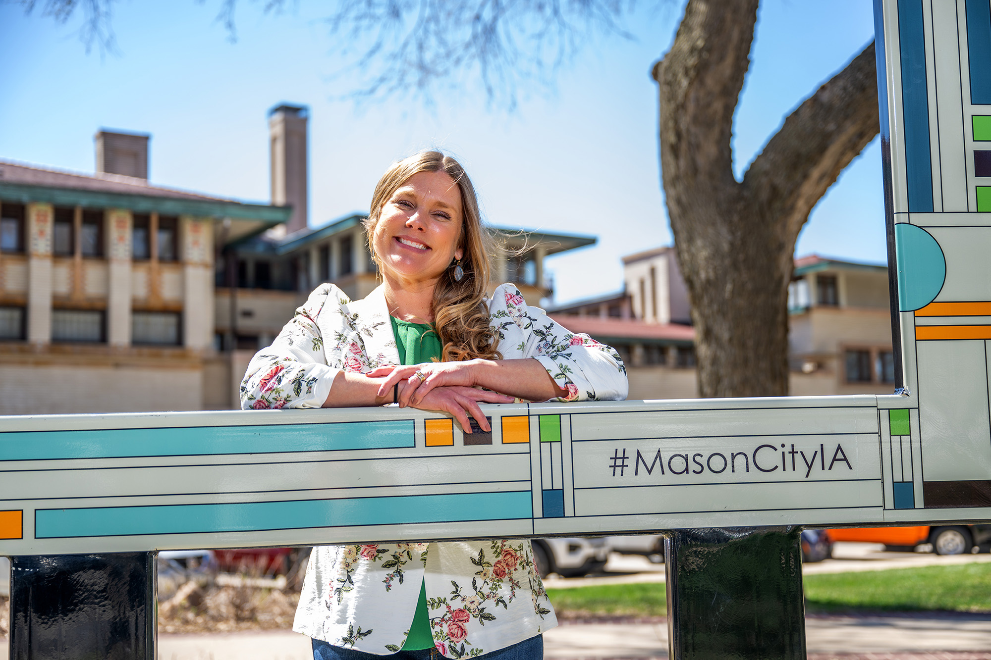 a woman posing for a photo near signage that touts Mason City