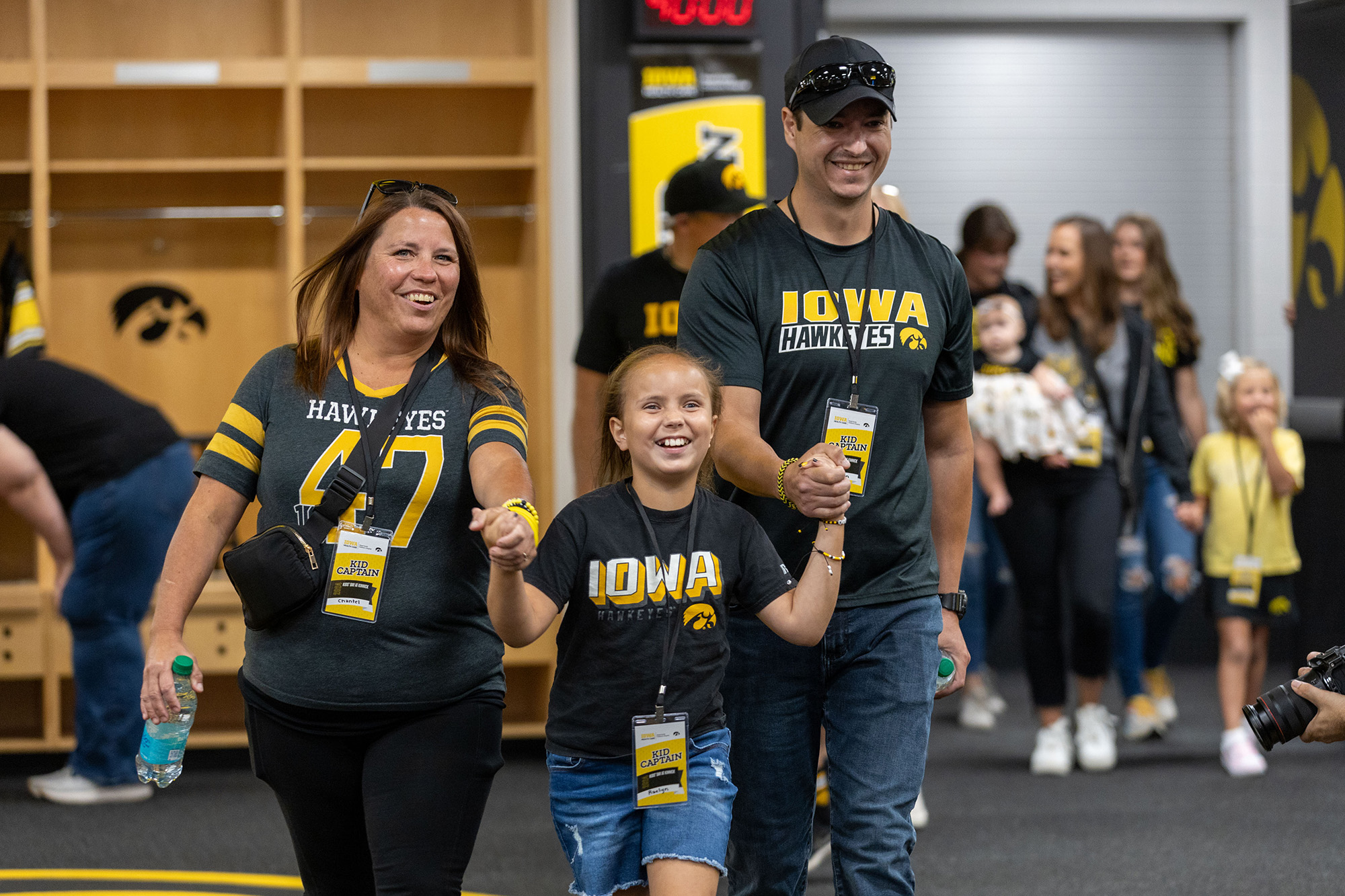 Kid Captain Raelyn Miller-Ramirez with her parents in the locker room at Kinnick Stadium