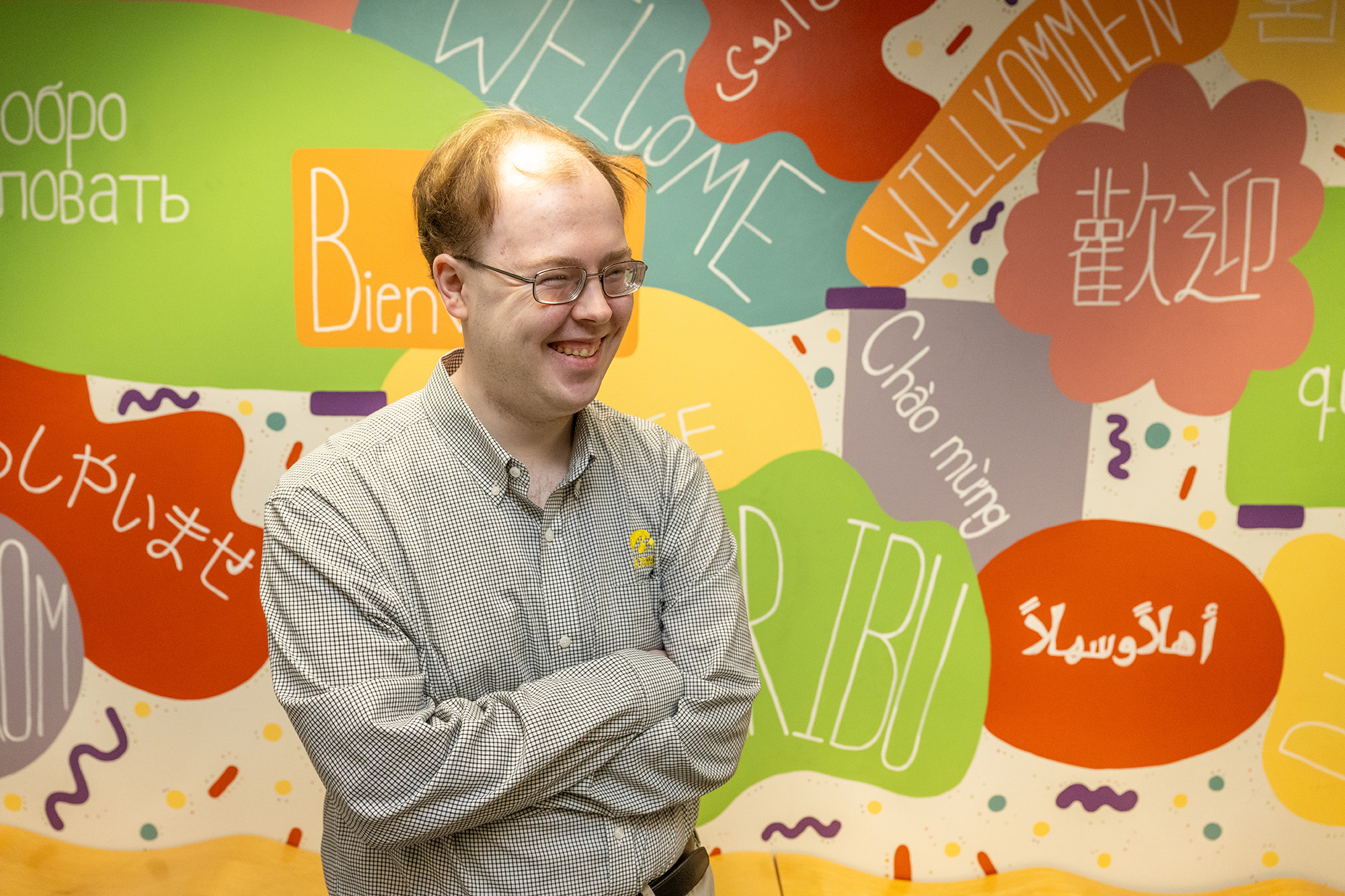 a young man stands in a hallway with a colorful mural in the background