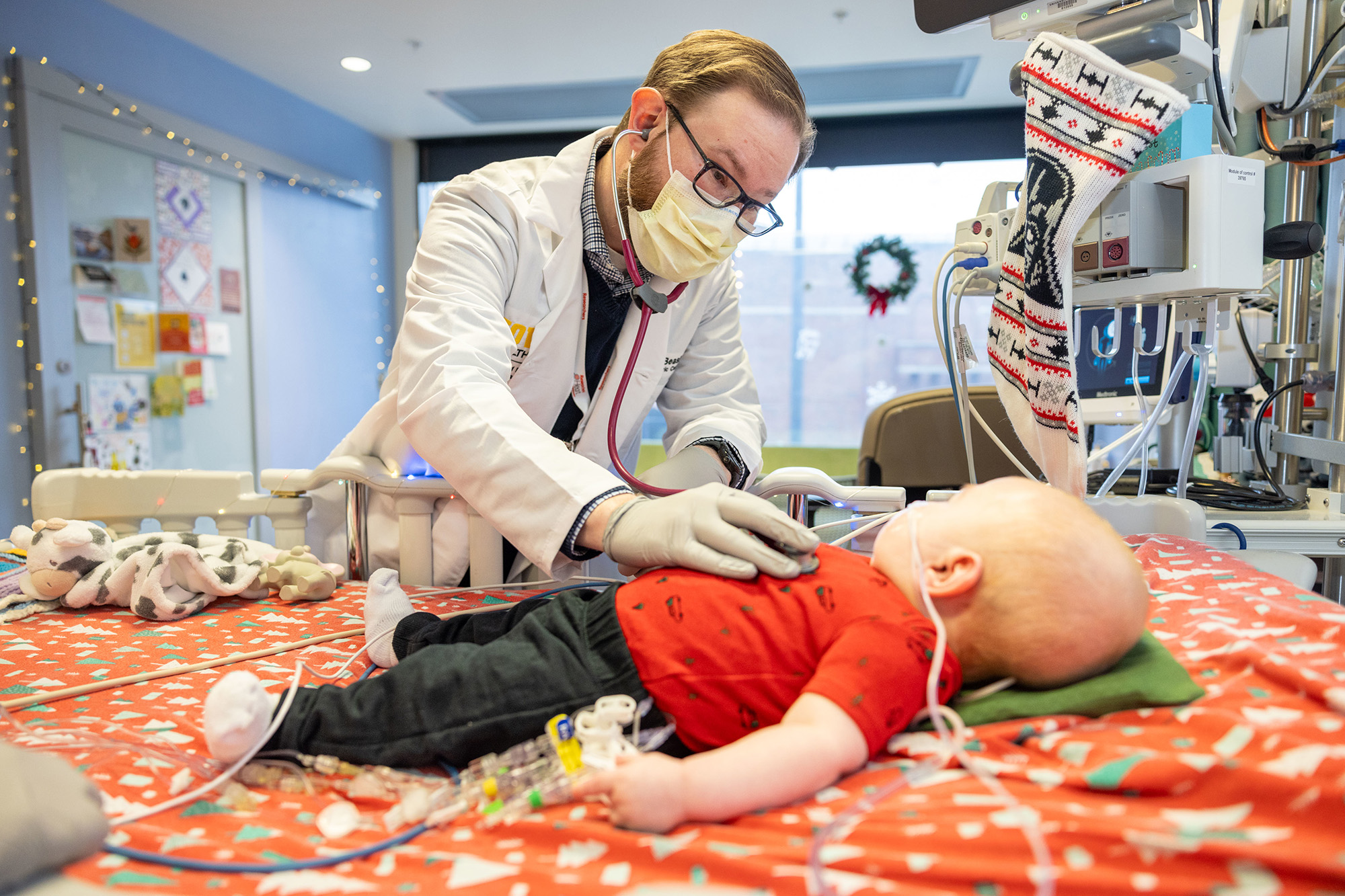 a cardiologist examines an infant in a hospital room