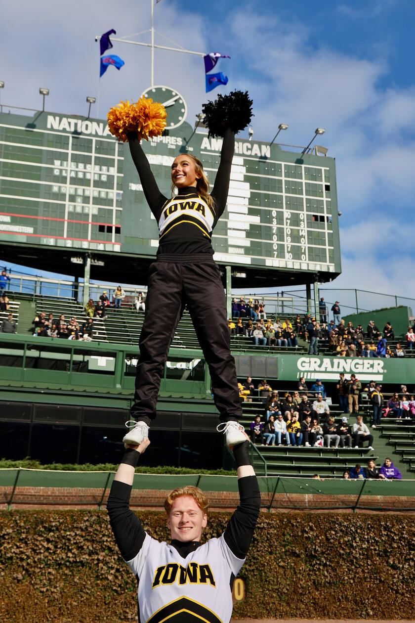 Two cheerleaders performing a routine in front of a crowd