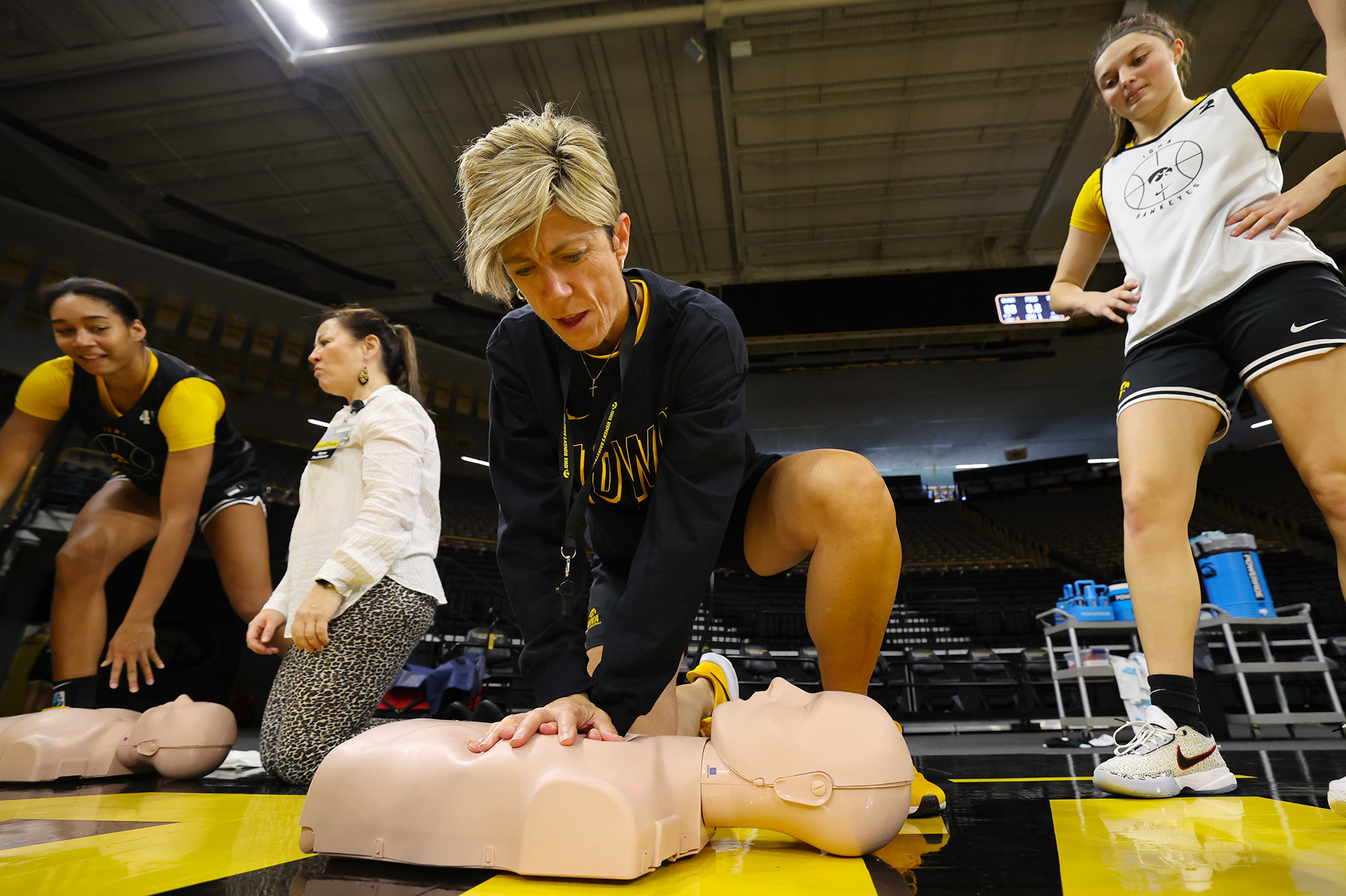 A woman crouching down over a dummy performing CPR