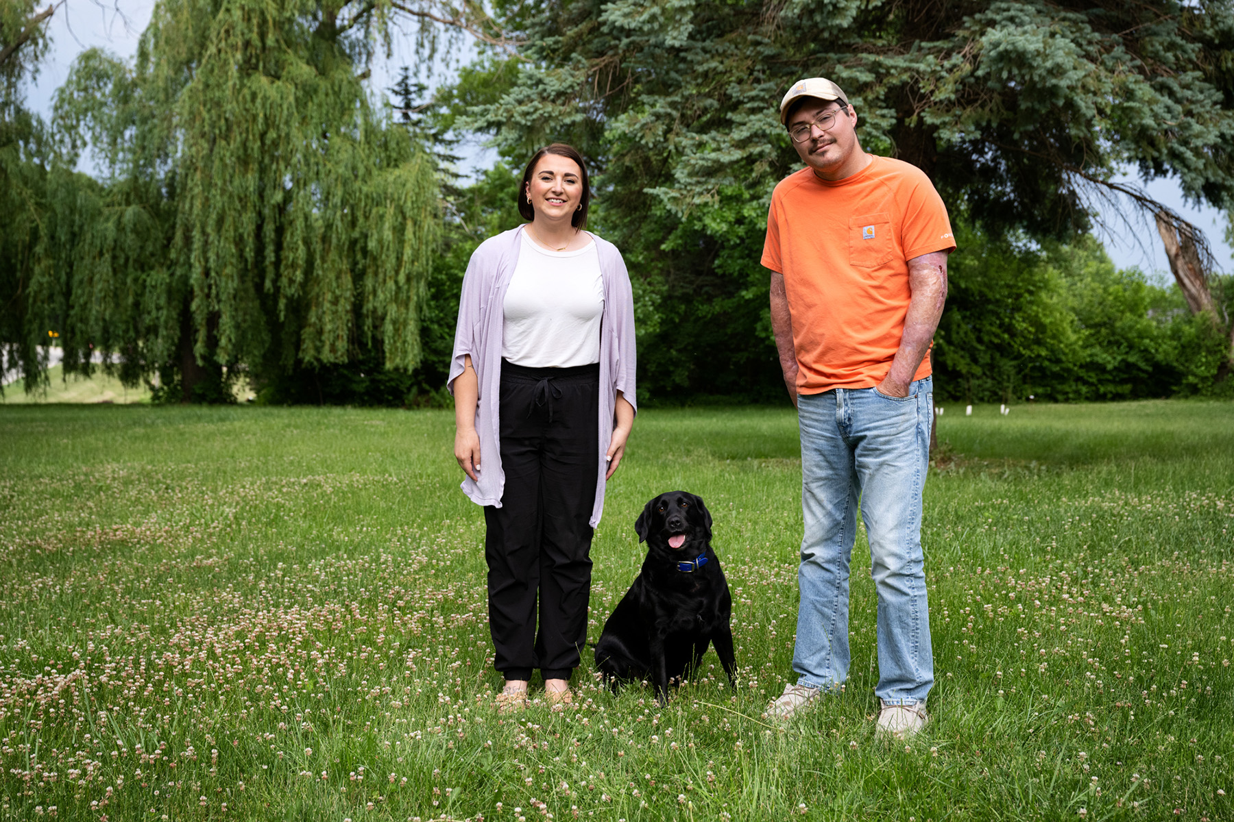A couple standing in a field with their dog
