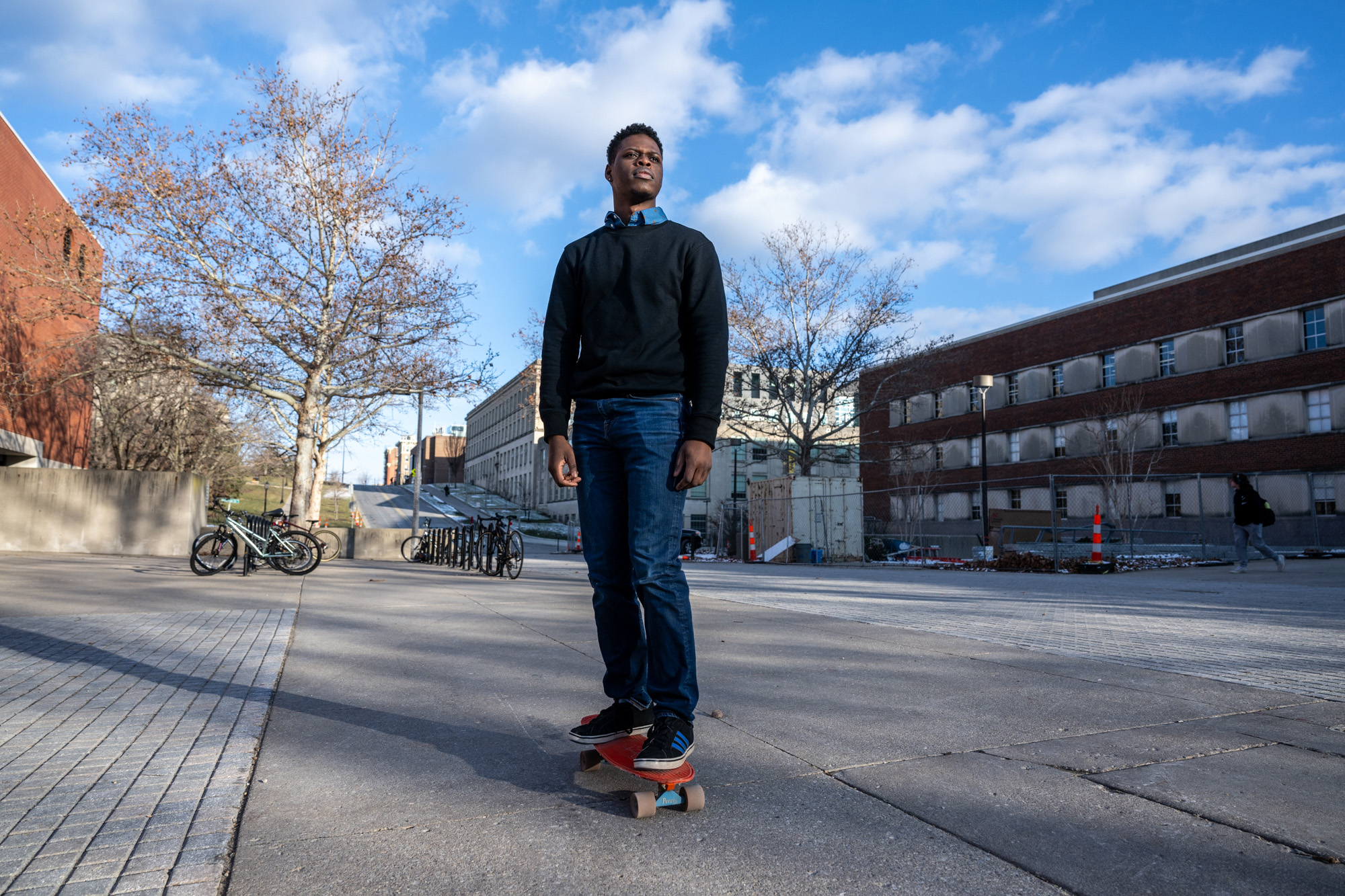 A man standing on a skateboard rolling down a hill