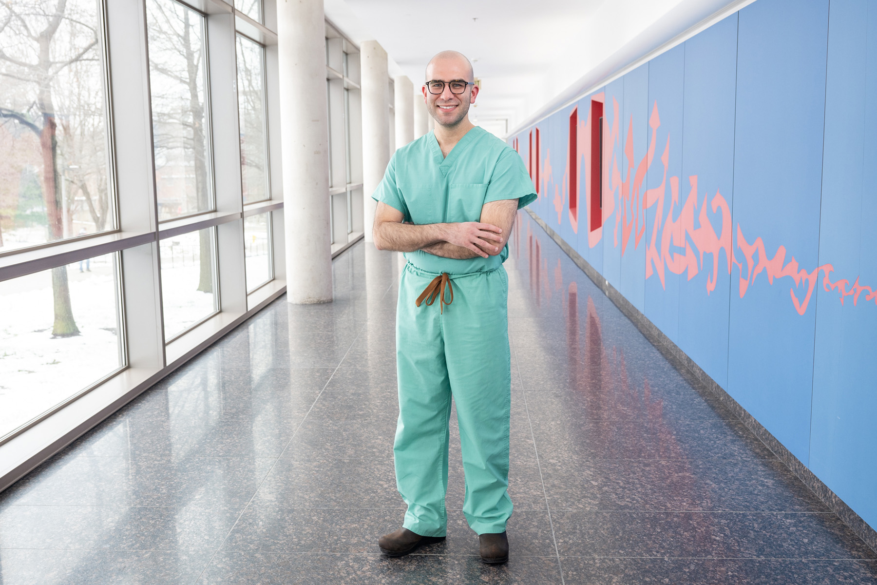 A man standing in a hallway with his arms crossed