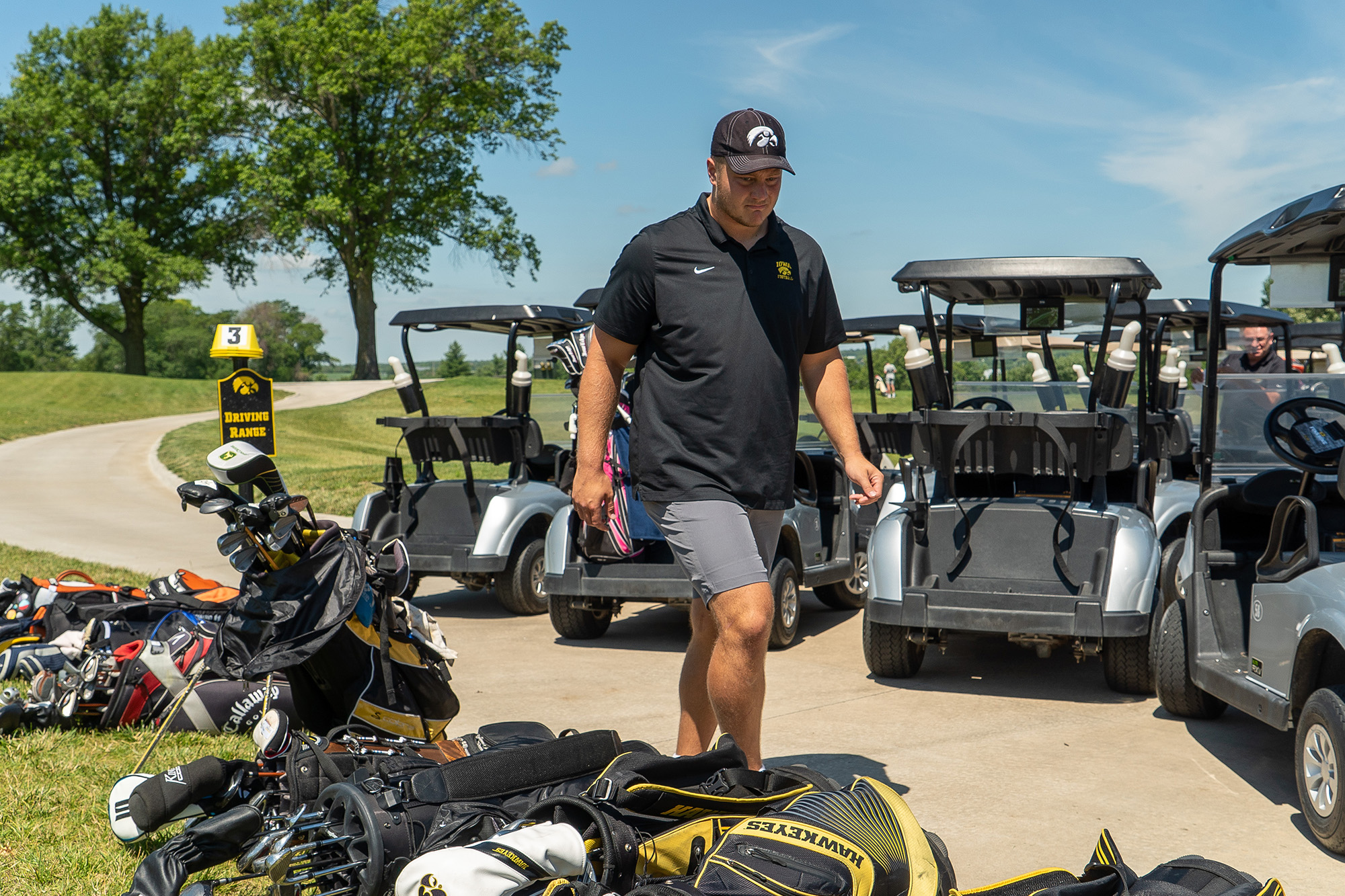 A man walking towards a set of golf clubs