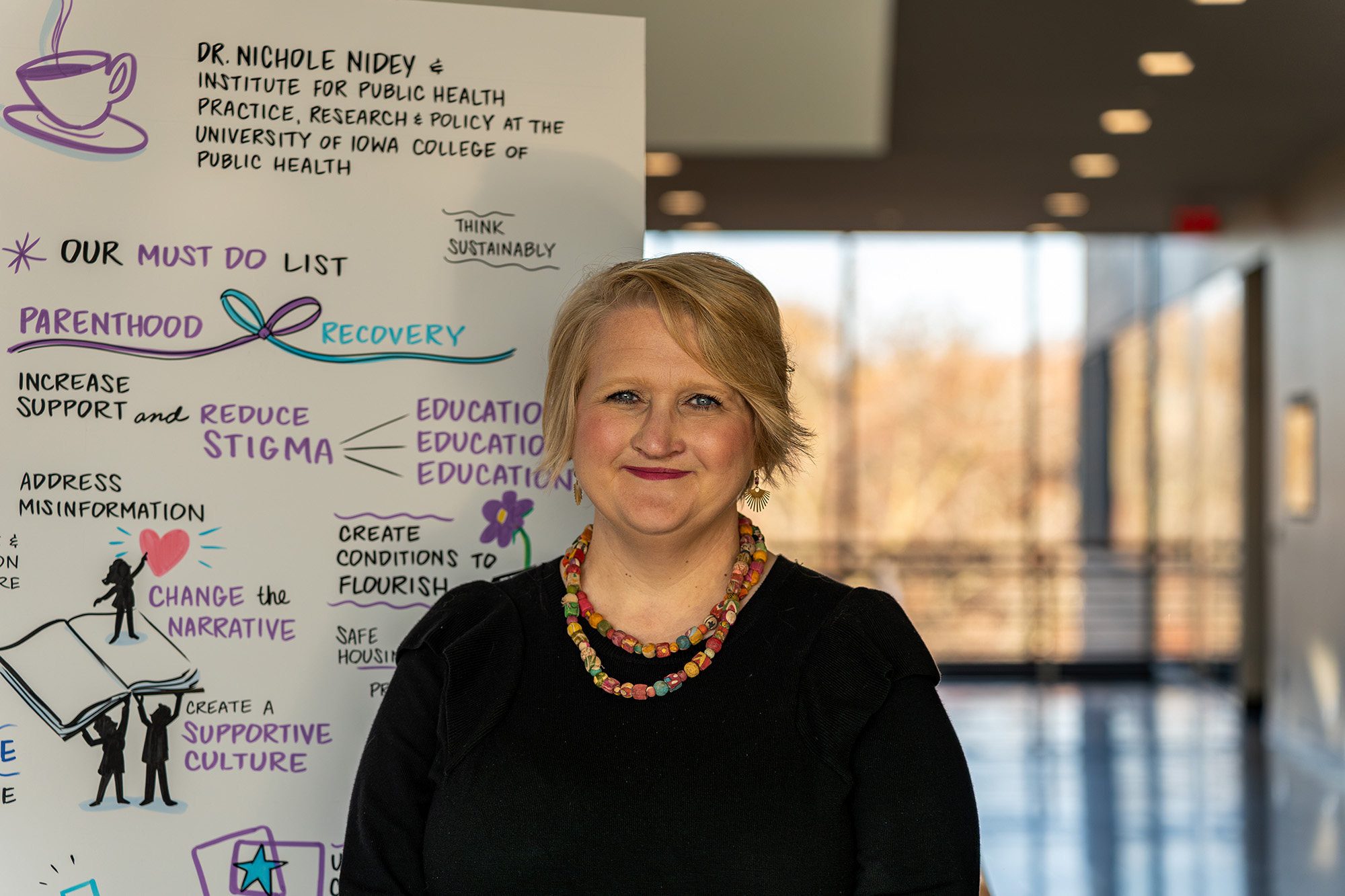 A woman standing in front of a poster that says "reduce stigma"