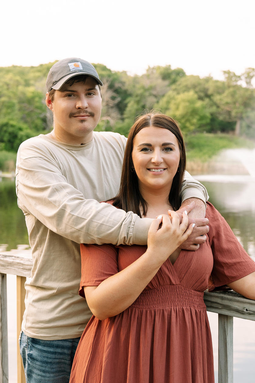 A man and woman embracing each other while standing next to a lake