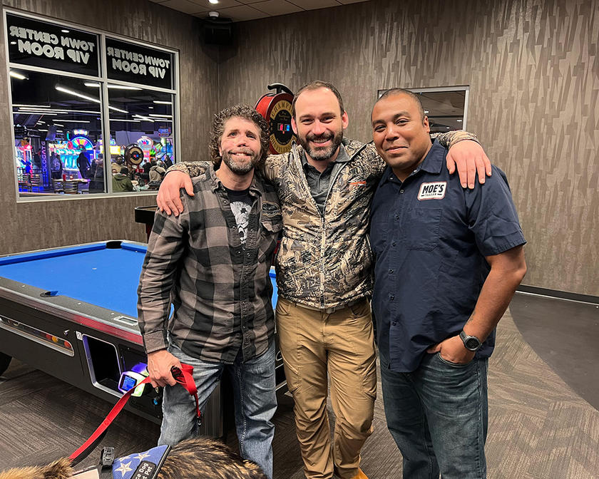 three men standing together smiling at the camera