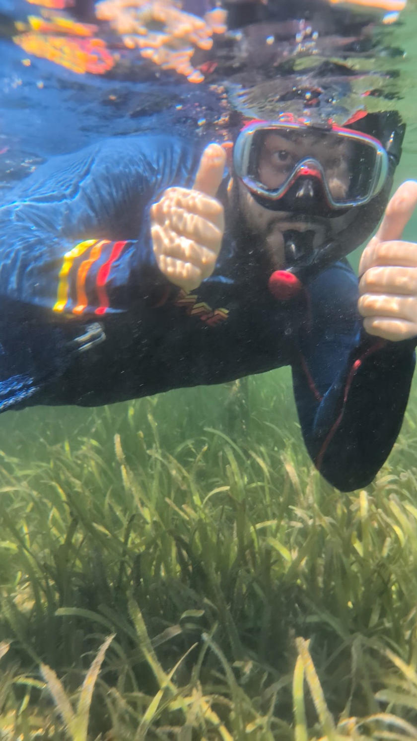 A man snorkeling and giving two thumbs up