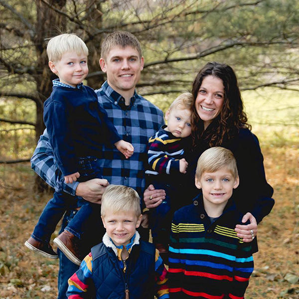 A family of six standing in a forest smiling for a photo