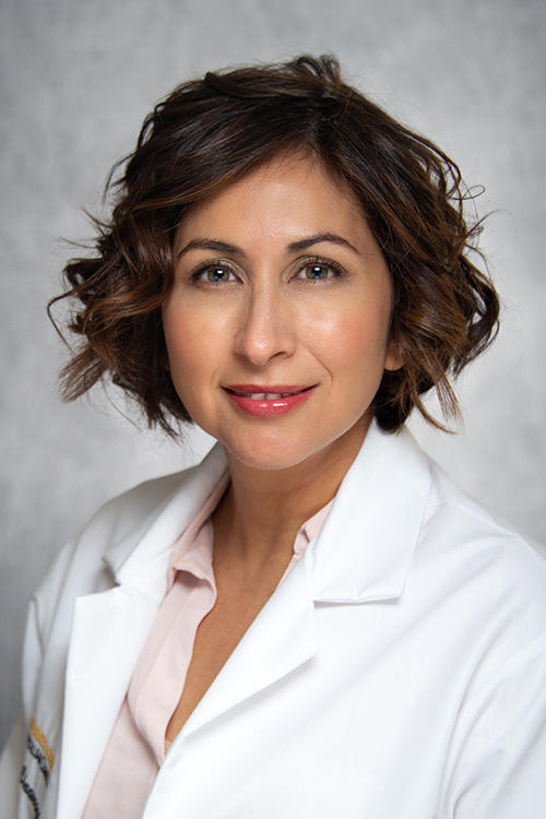 A woman smiling for a portrait in a lab coat