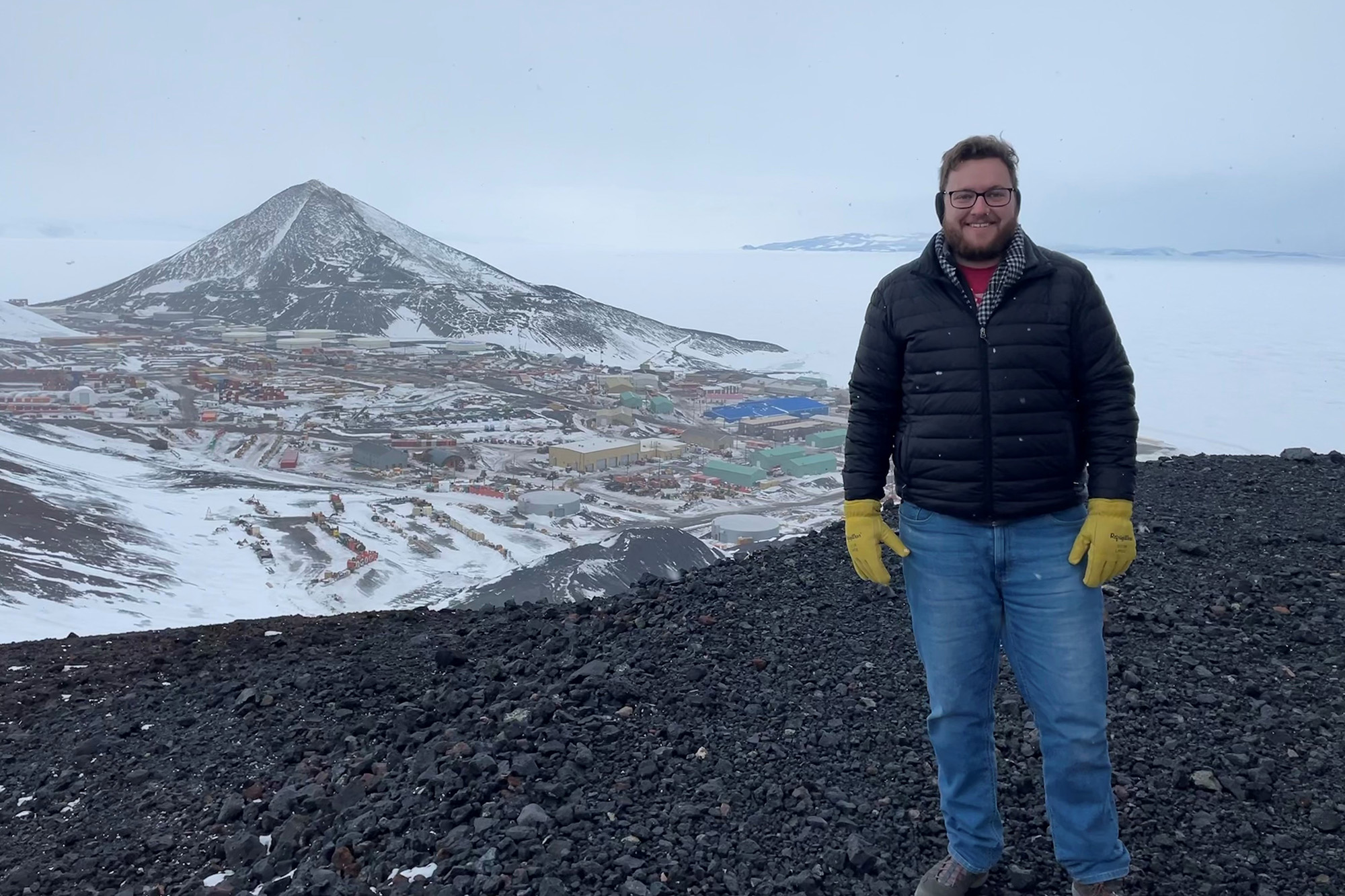 A man smiling standing on the top of a mountain