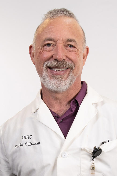A man in a labcoat smiling