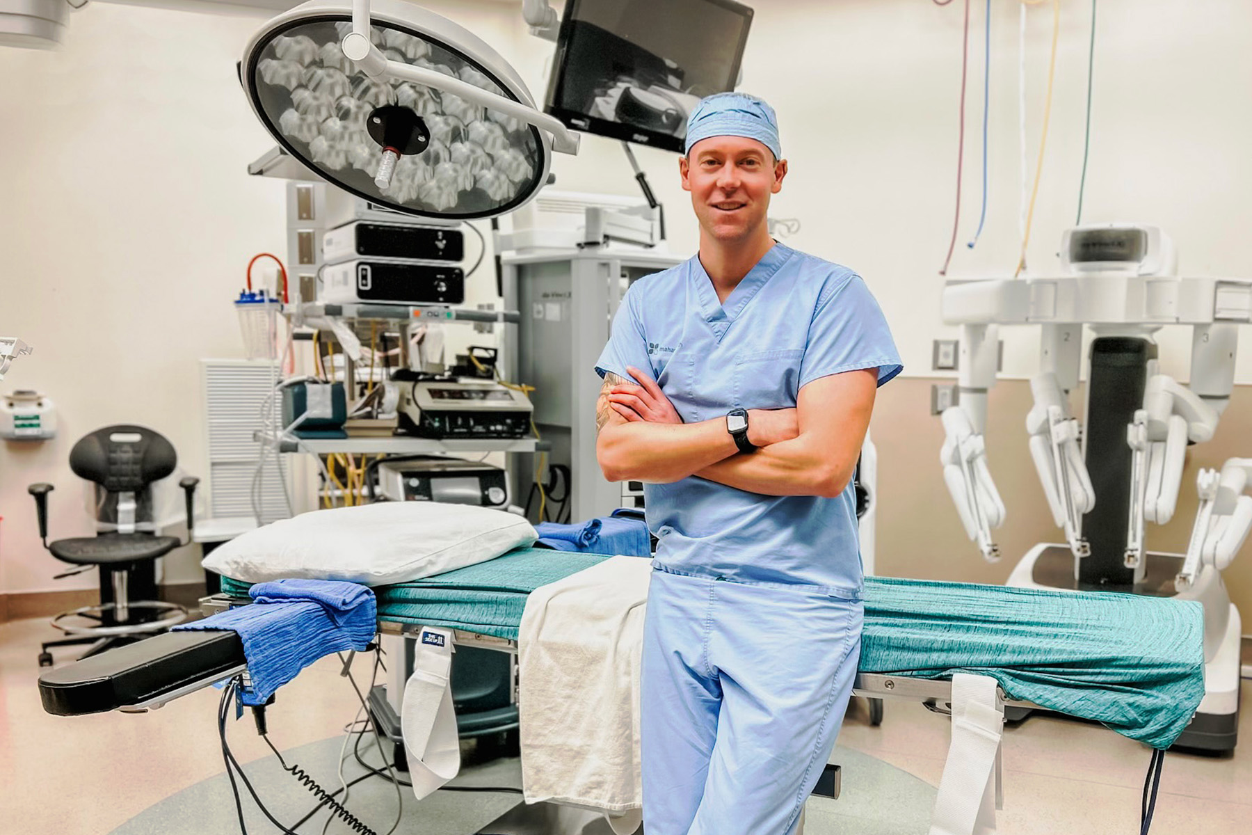 A doctor in scrubs leaning against a hospital bed