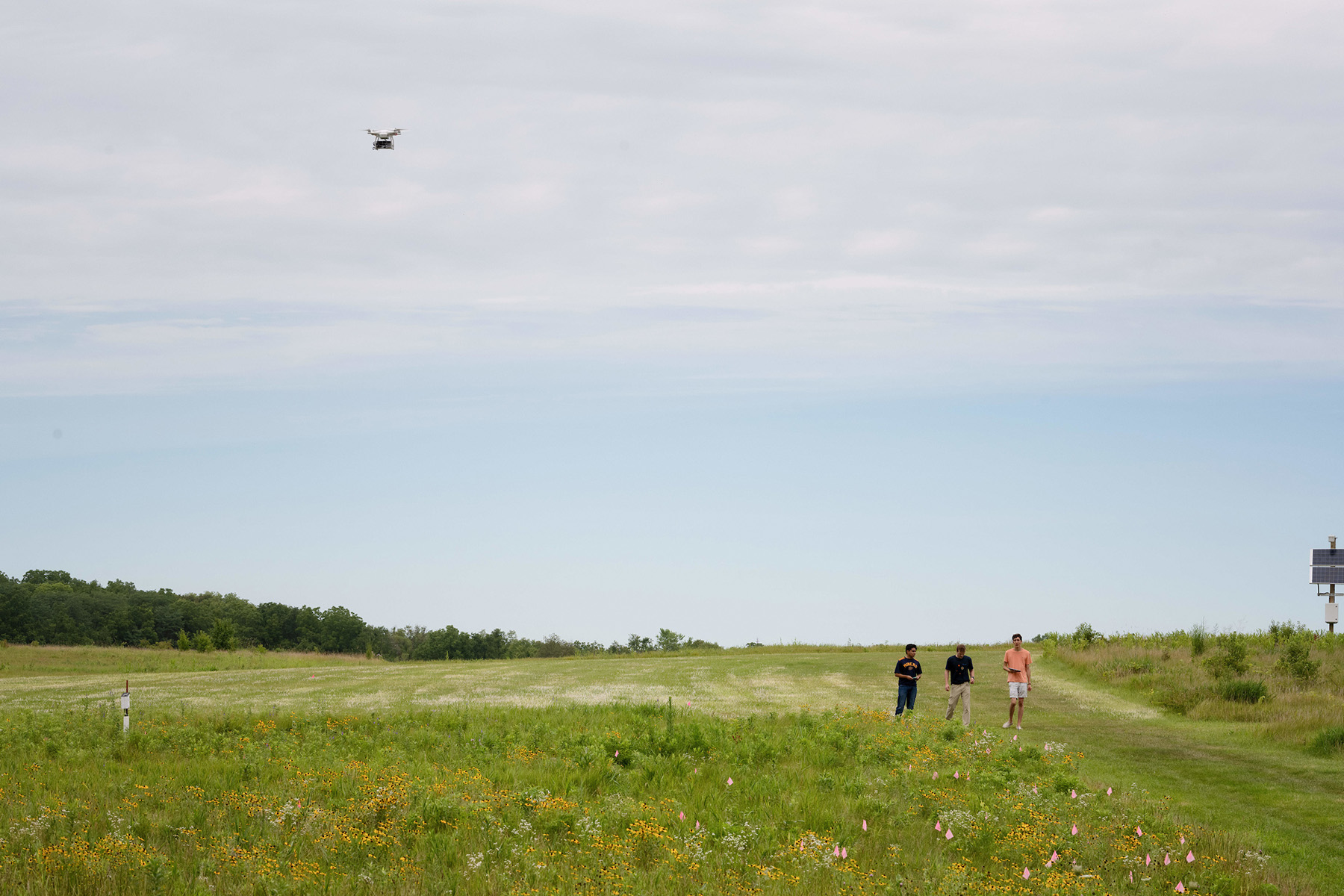 students in a field flying a drone