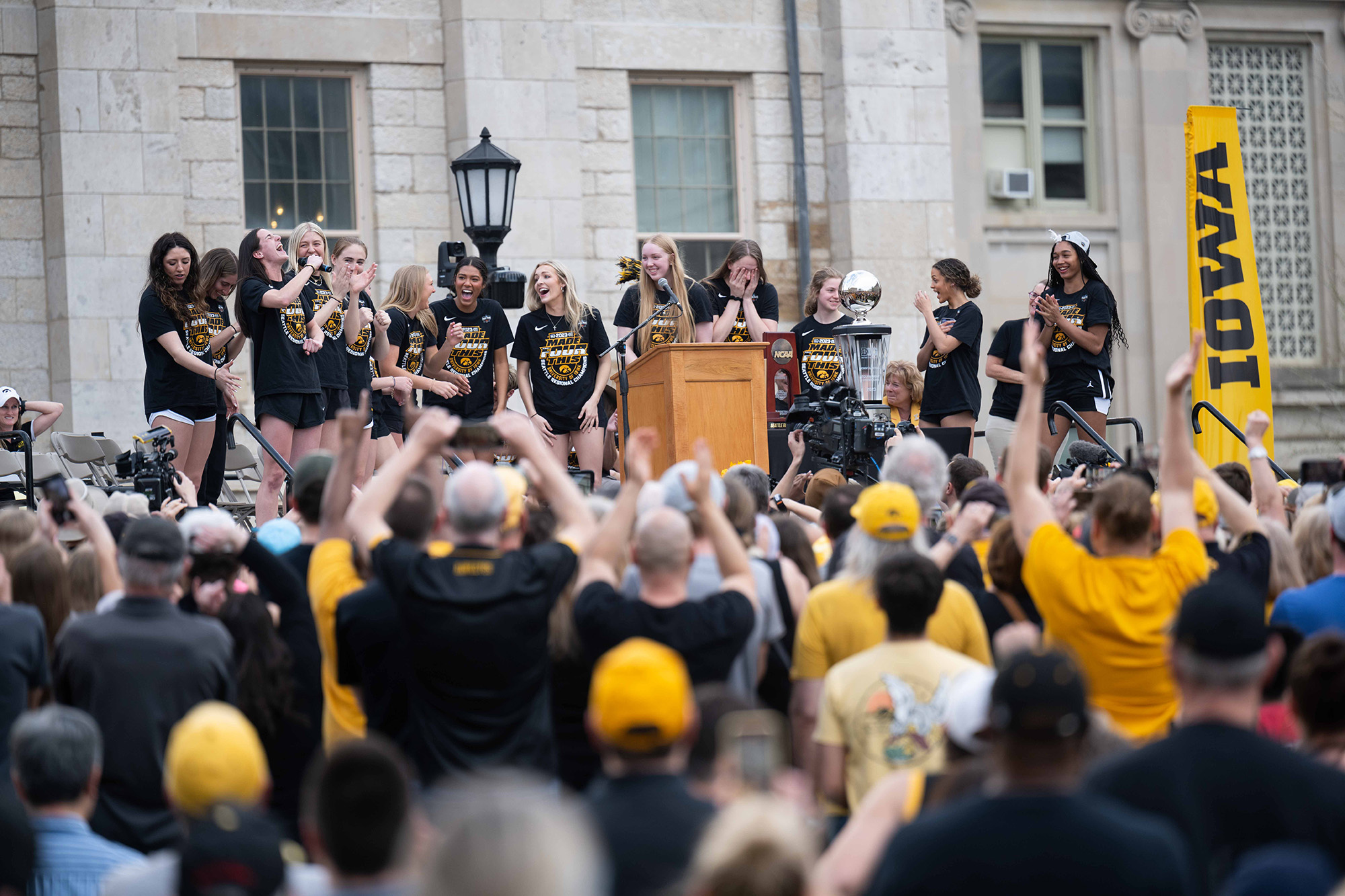 A group of peple on stage with a cheering crowd below them