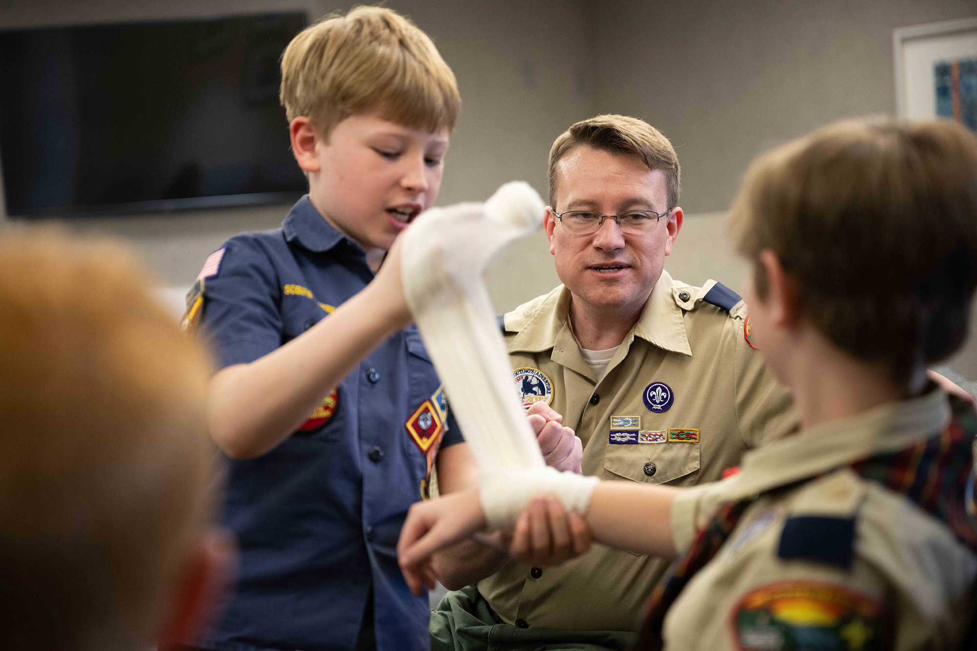 A man teaching kids how to apply a bandage