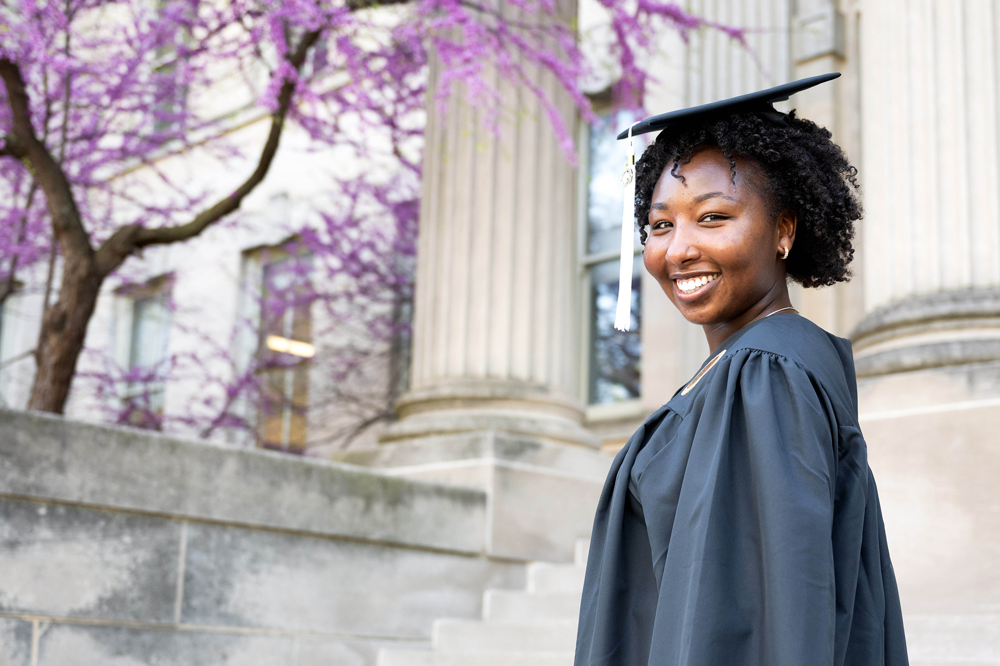 A woman standing on a set of steps in a cap and gown