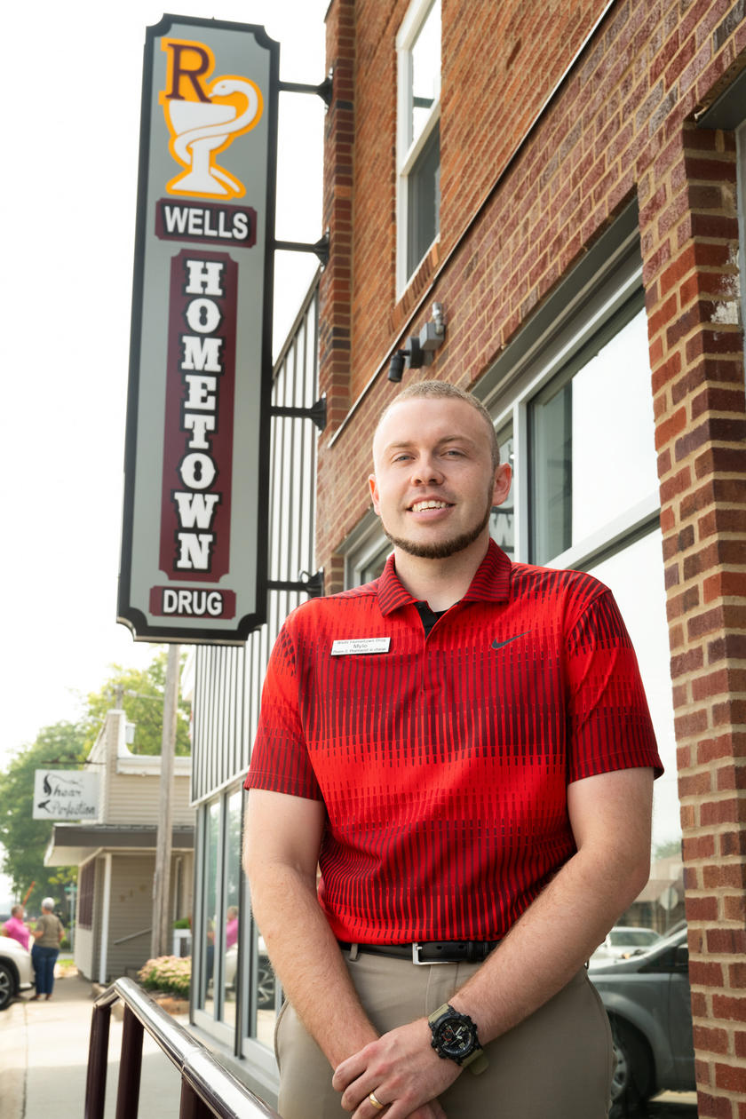 A man sitting outside a drug store smiling