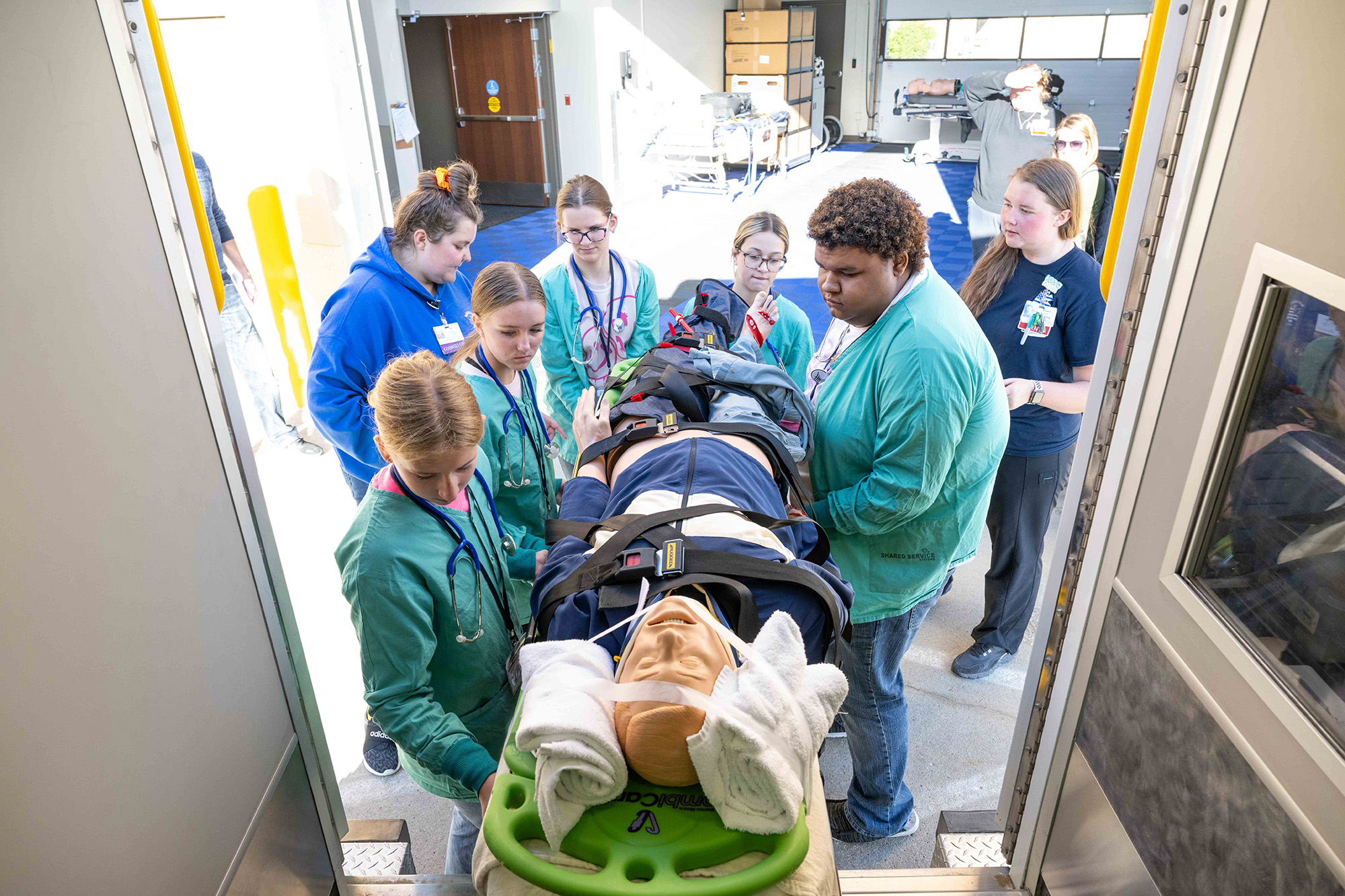 A group of people putting a training dummy in an ambulance