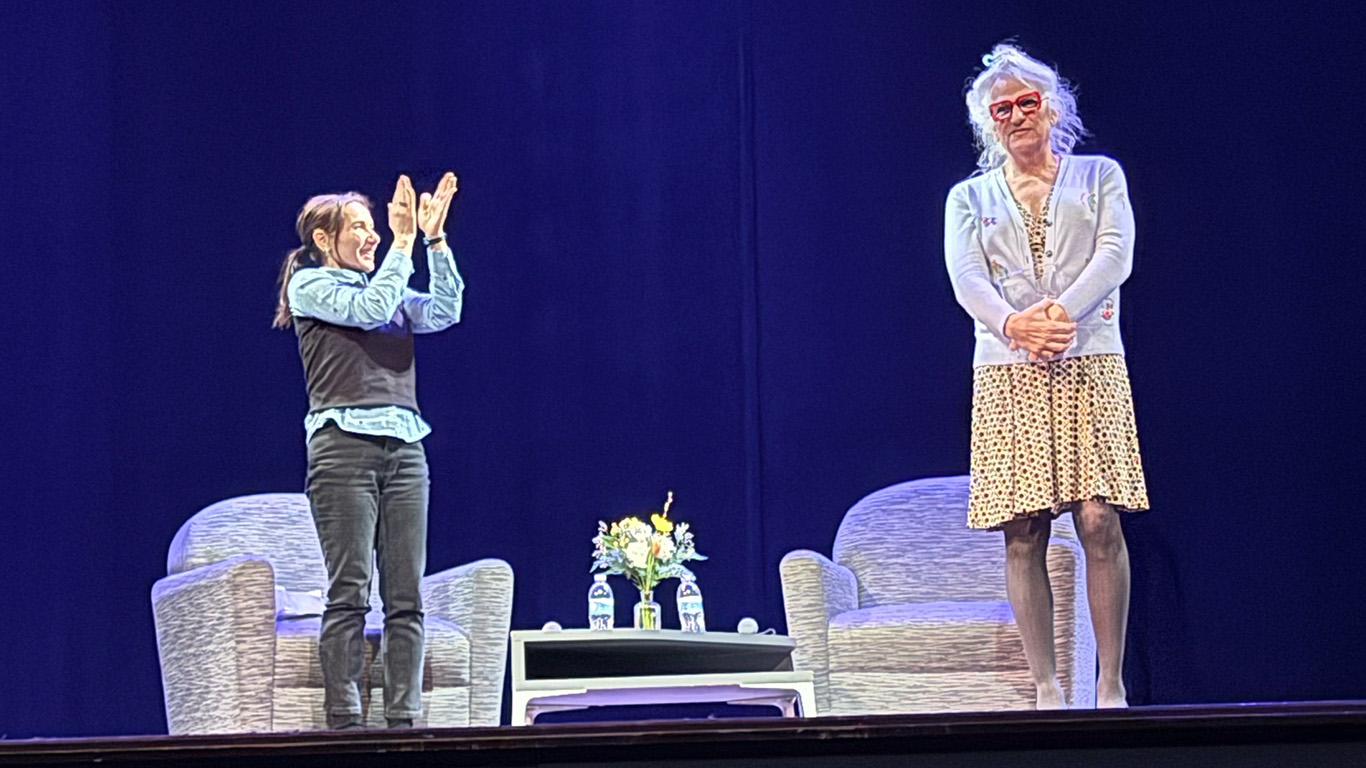University of Iowa English professor and author Melissa Febos applauds while standing on the Englert Theatre stage with Harper Steele