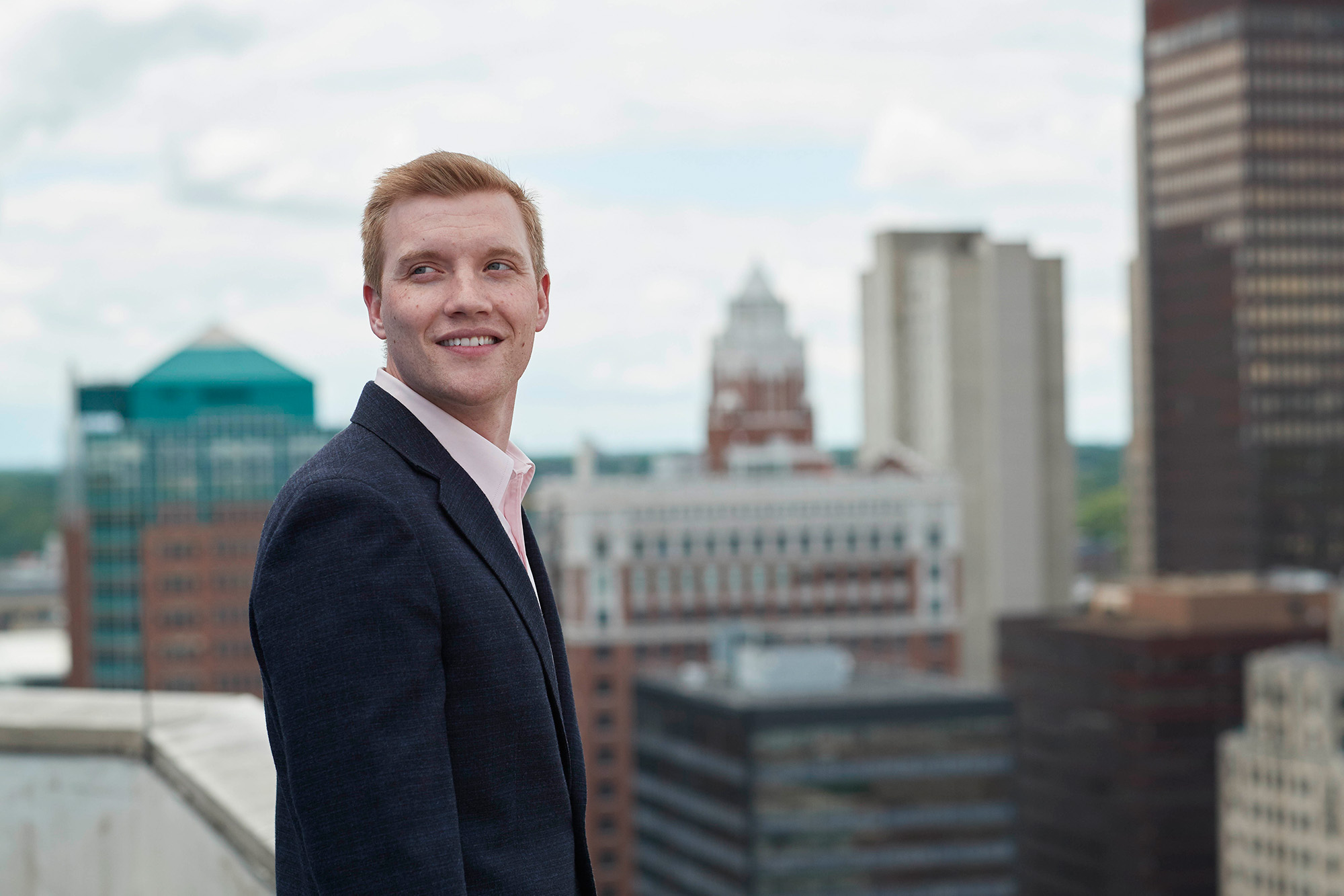 A man standing on top of a roof with a city in the background