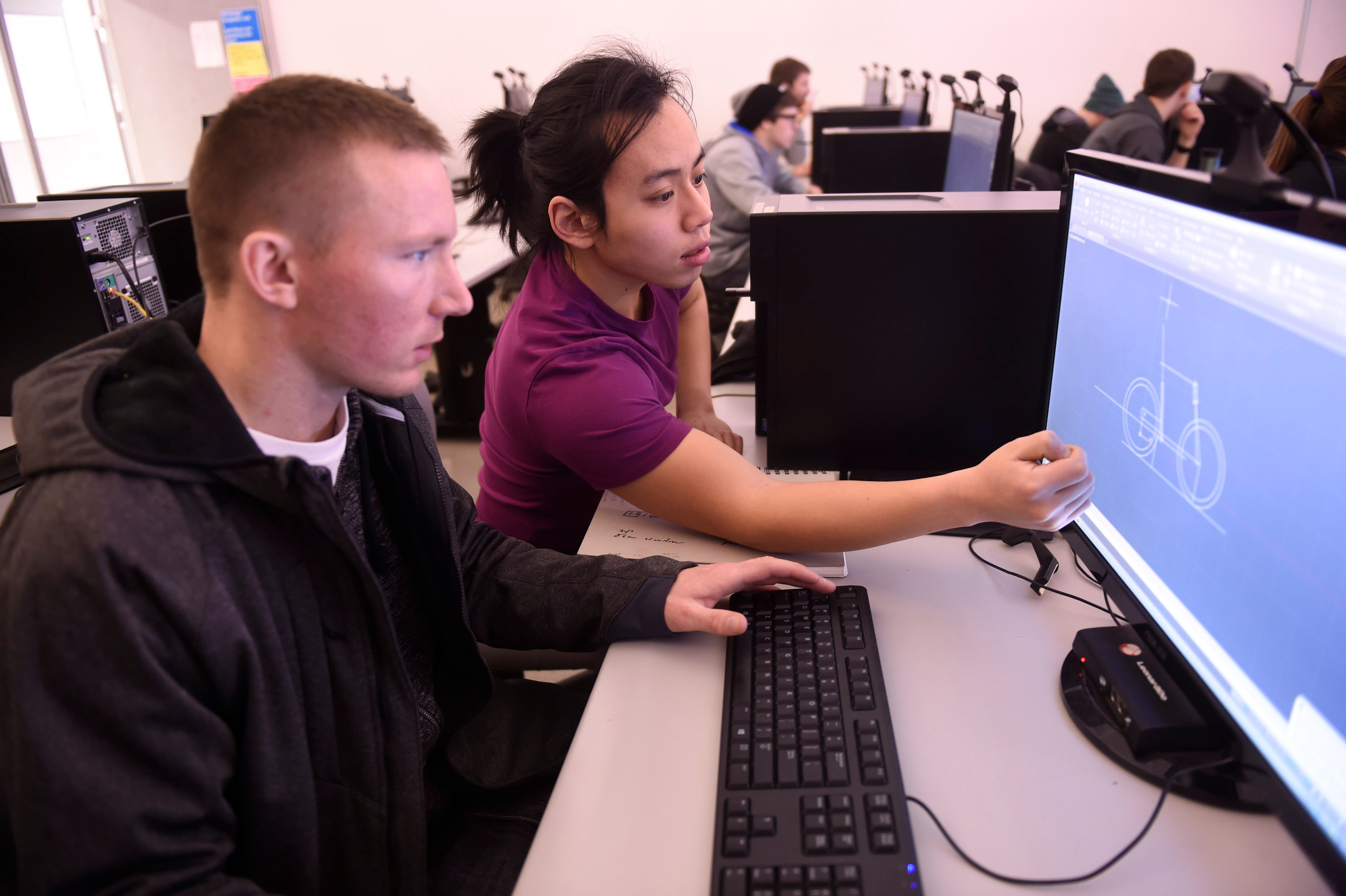 Two people looking at blueprints on a computer