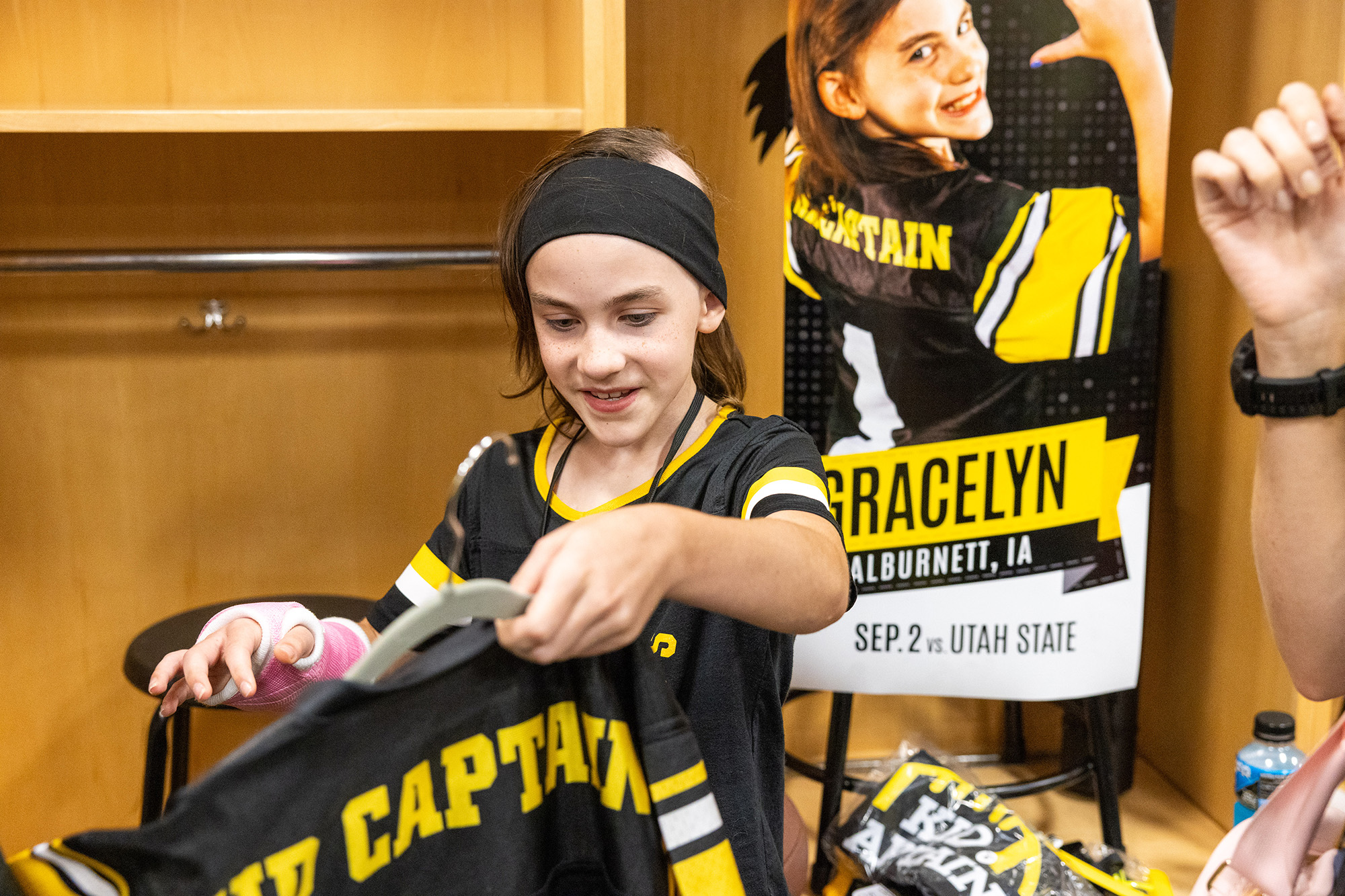 A young girl holding up a kid captain shirt