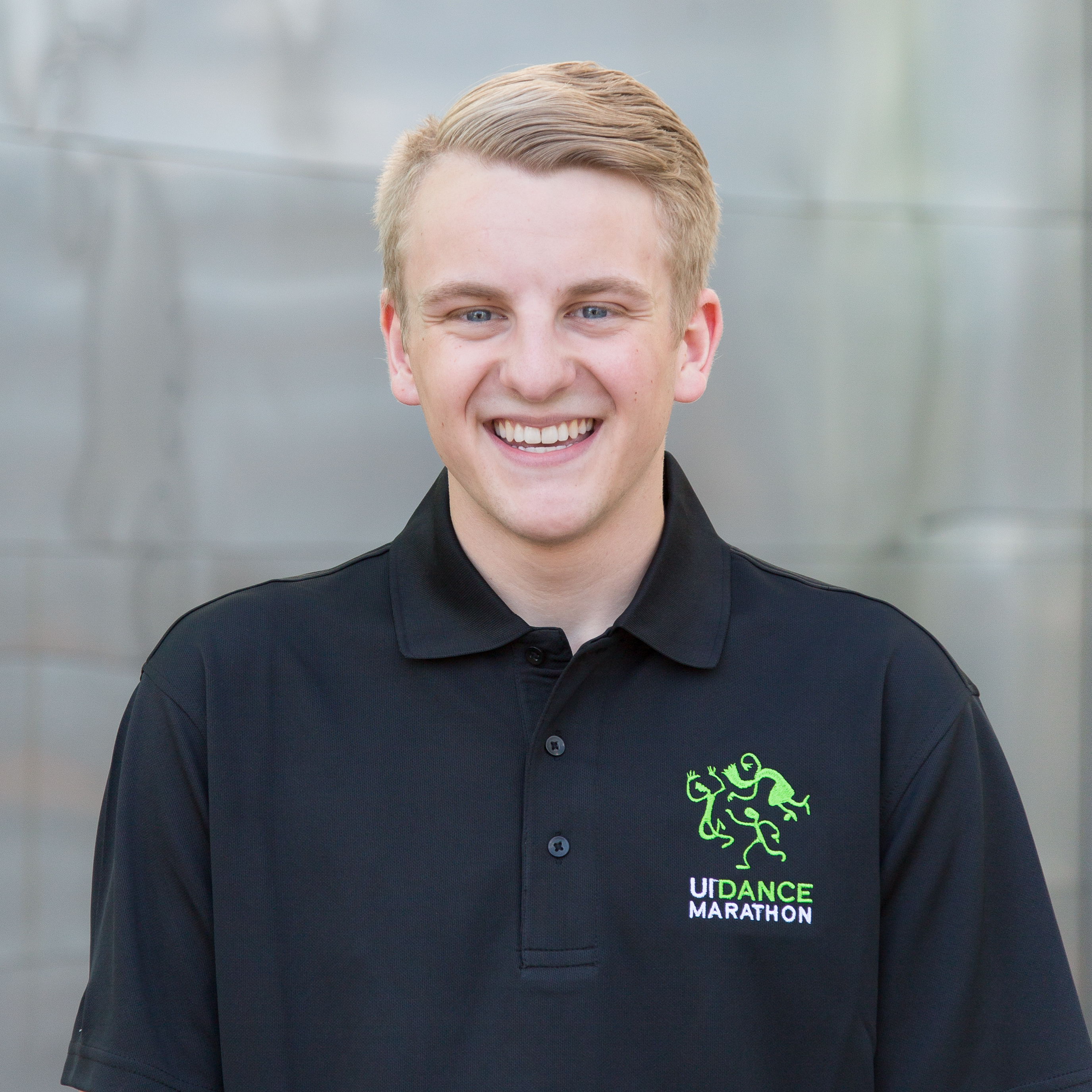 A young man smiling and wearing a dance marathon shirt