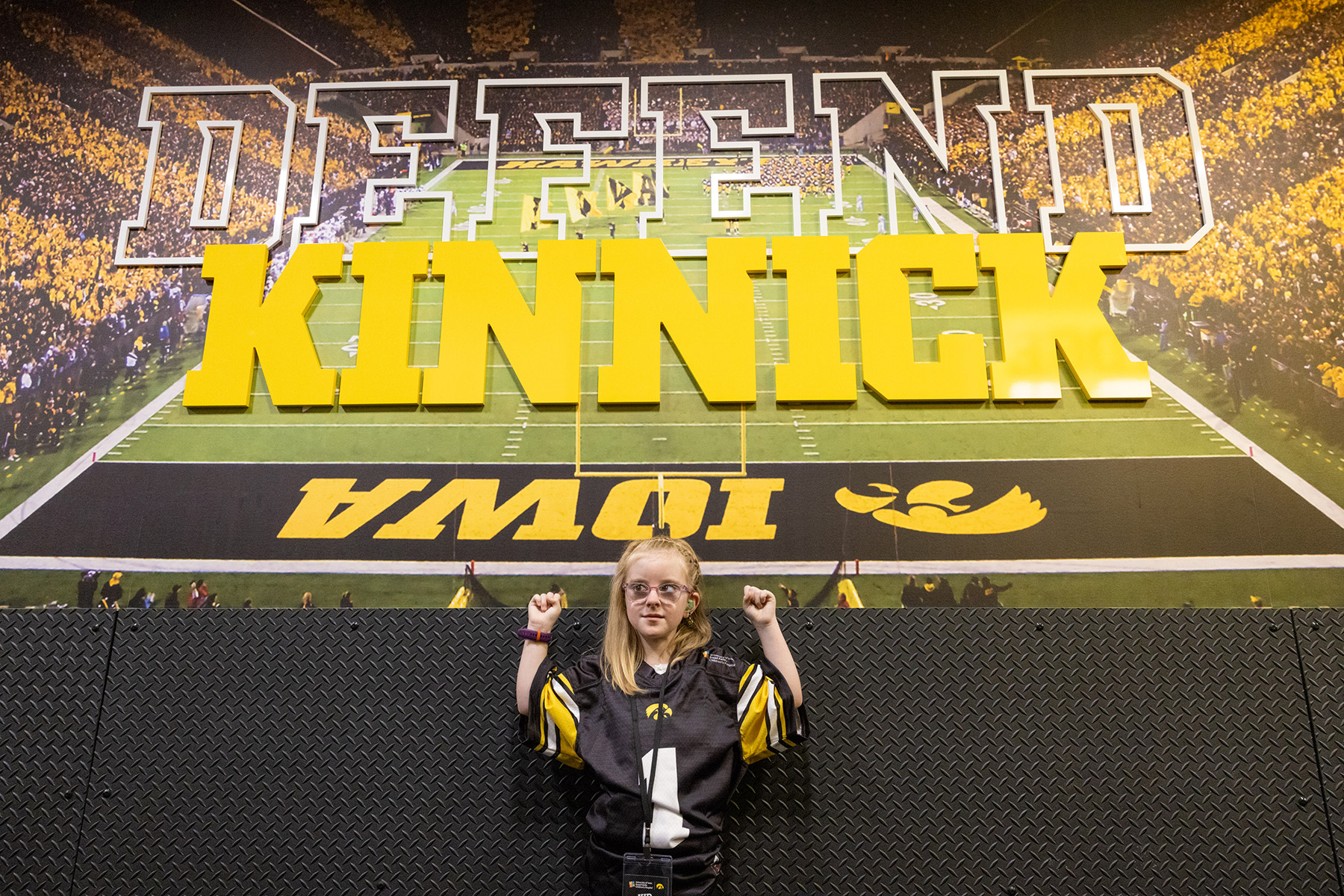 A girl standing in front of an image of a stadium cheering