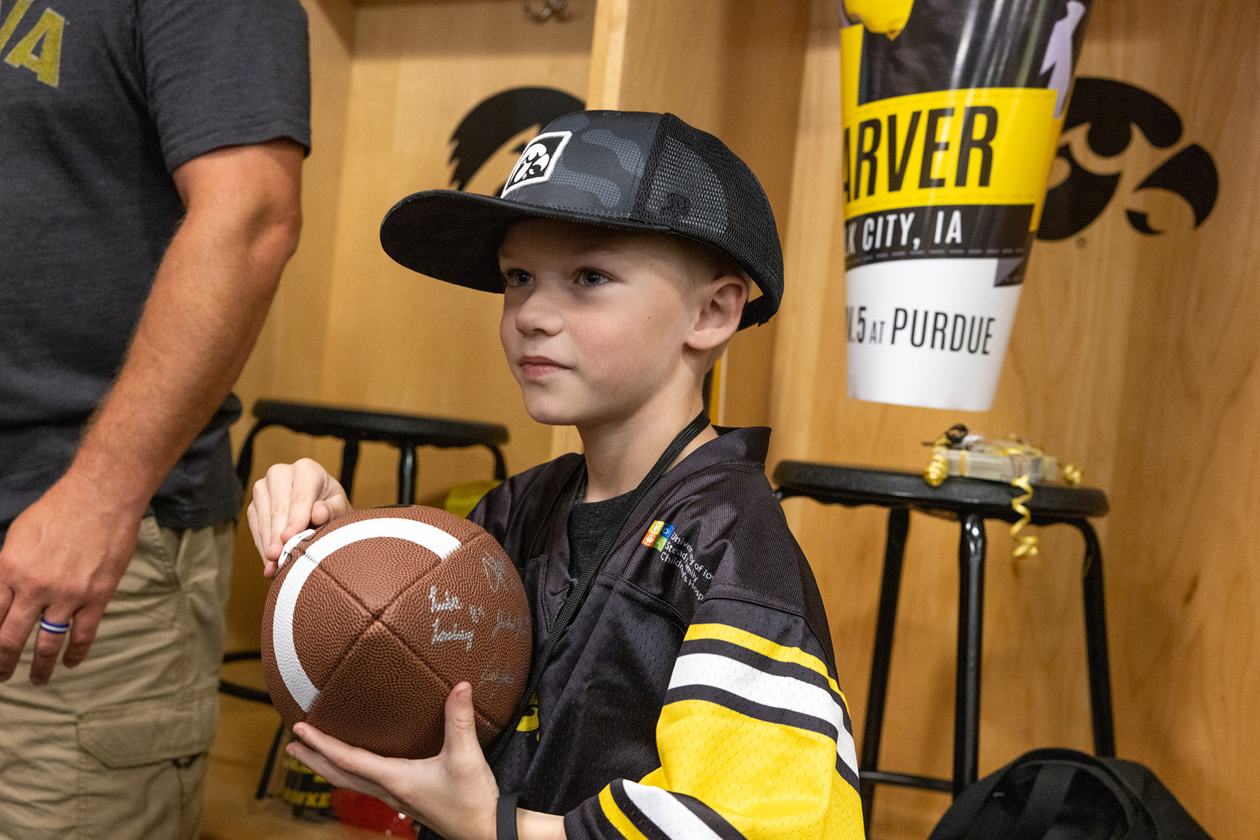 A kid wearing a hat and holding a football